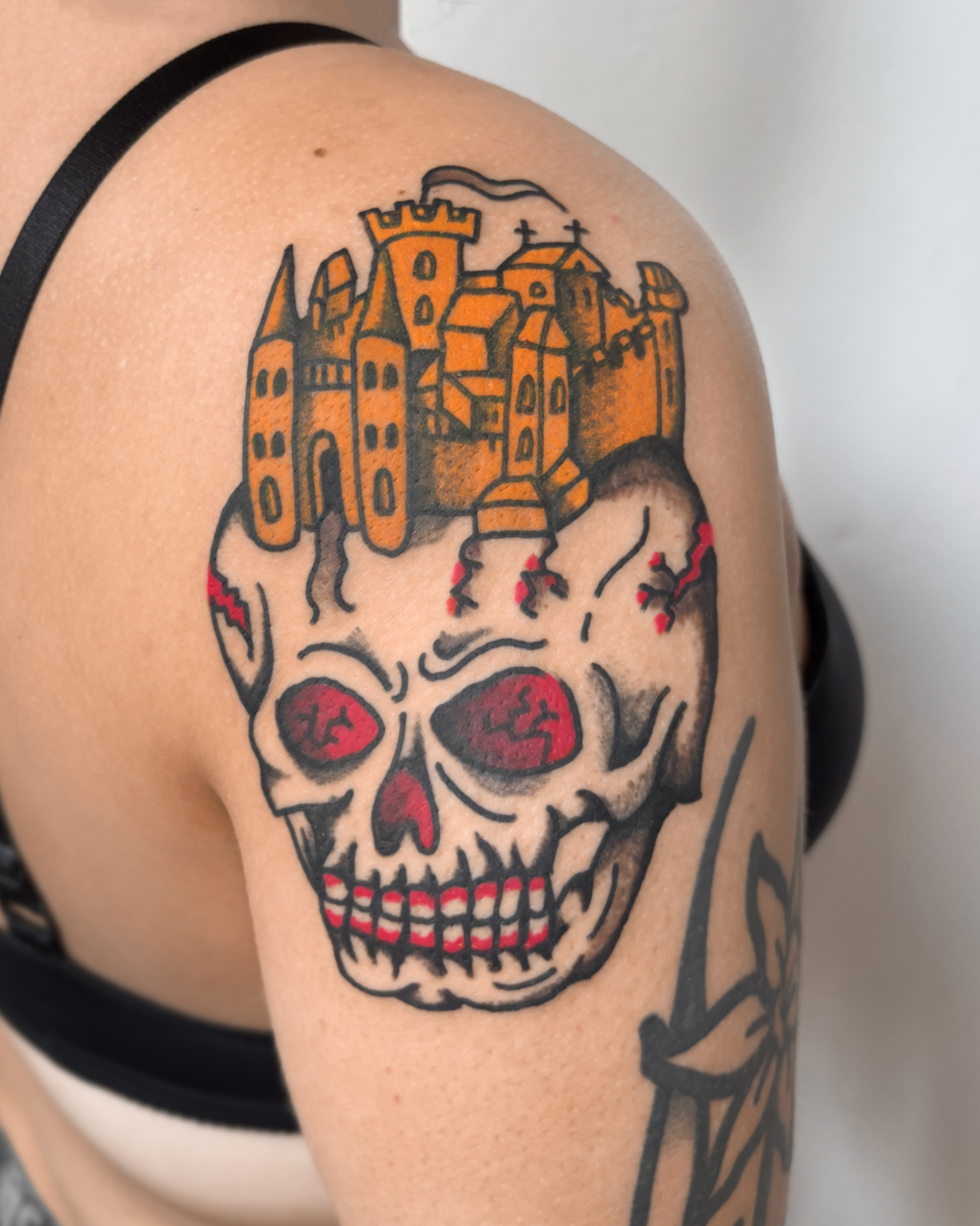 Tattoo of a skull with red eyes and a castle on top of its head.