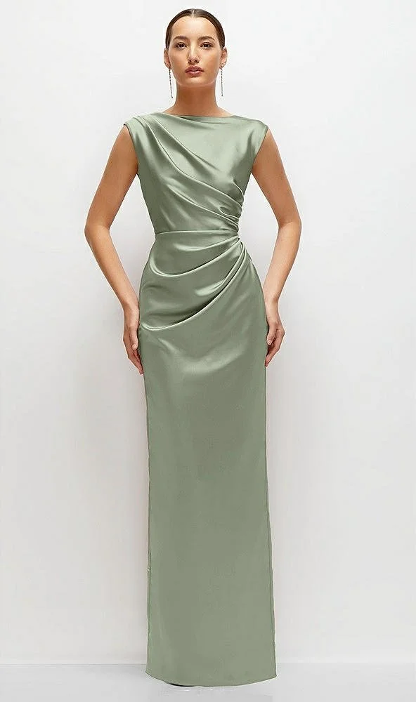 A woman in a long, satin, sage green evening gown with a draped design and sleeveless shoulders, standing against a plain white background.