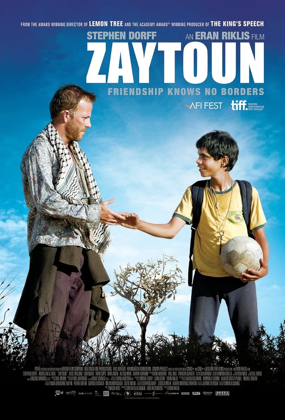 Movie poster for 'Zaytoun' featuring a man with a scarf and a young boy with a backpack holding a soccer ball, reaching out to shake hands against a partly cloudy sky background.