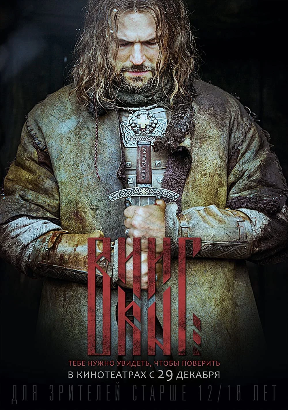 A man dressed as a medieval warrior, gripping a large ornate sword with both hands, wearing a rough, weathered tunic and armor. The image is promotional with Cyrillic text and release date.