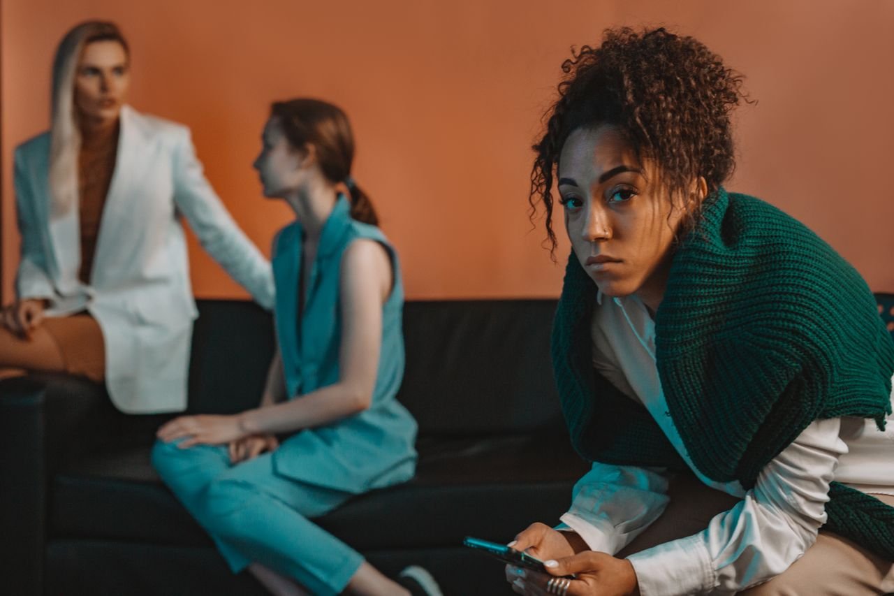 a woman sits further than her two companions on the couch