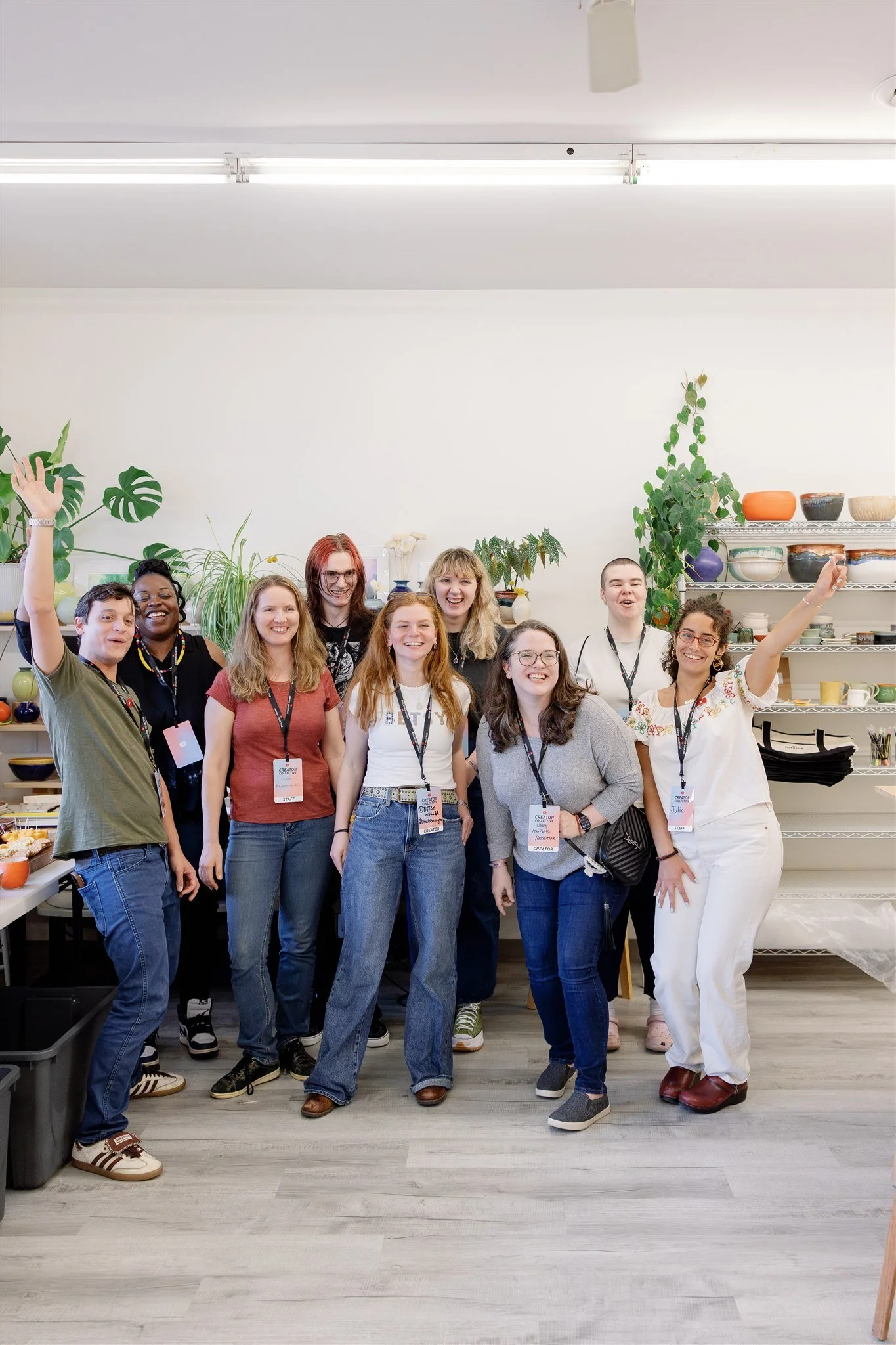 A group of people standing together in a room with shelves of bowls and plants in the background, smiling and posing for the photo.