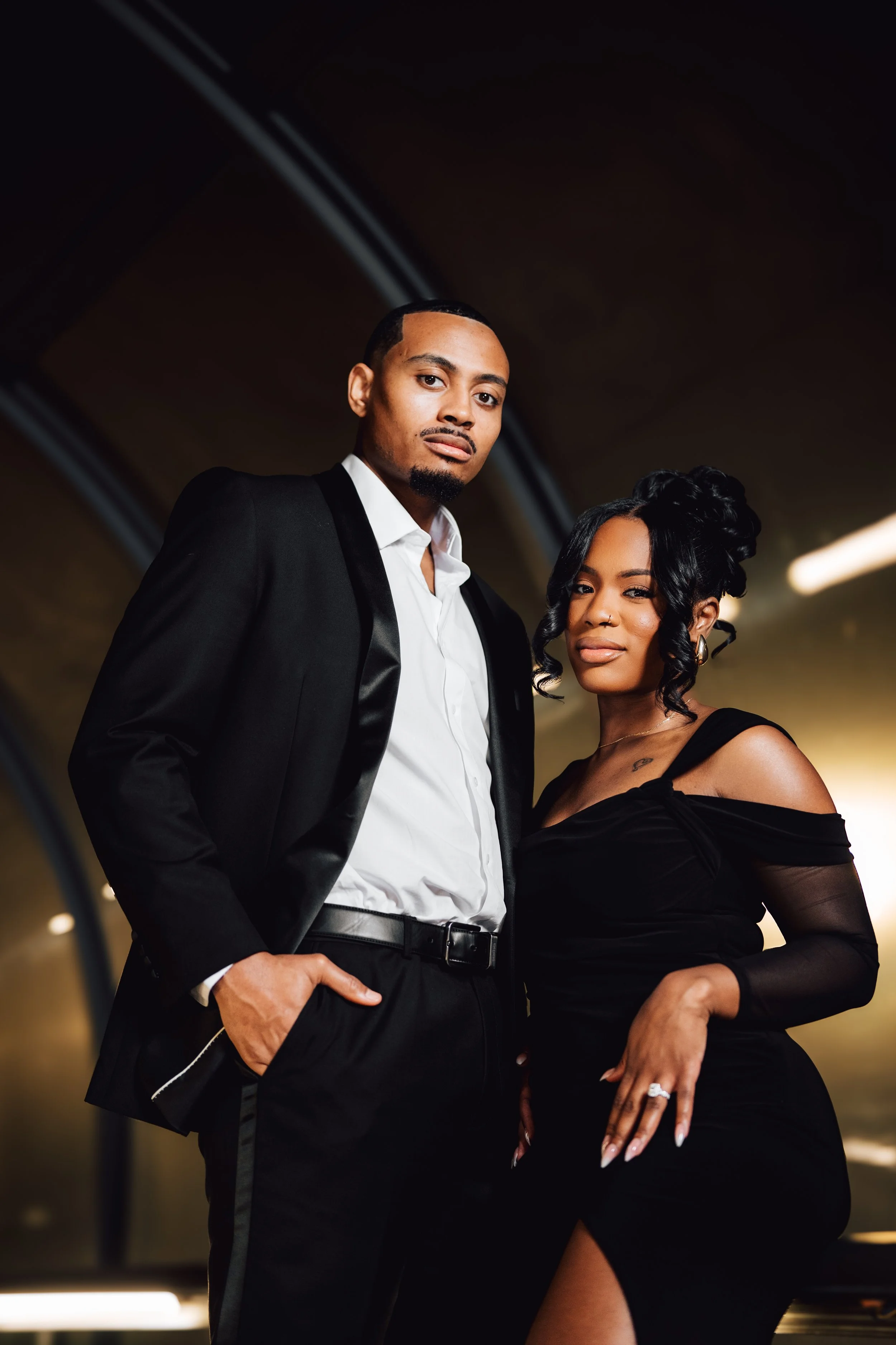A well-dressed man and woman posing together in a stylish indoor setting.