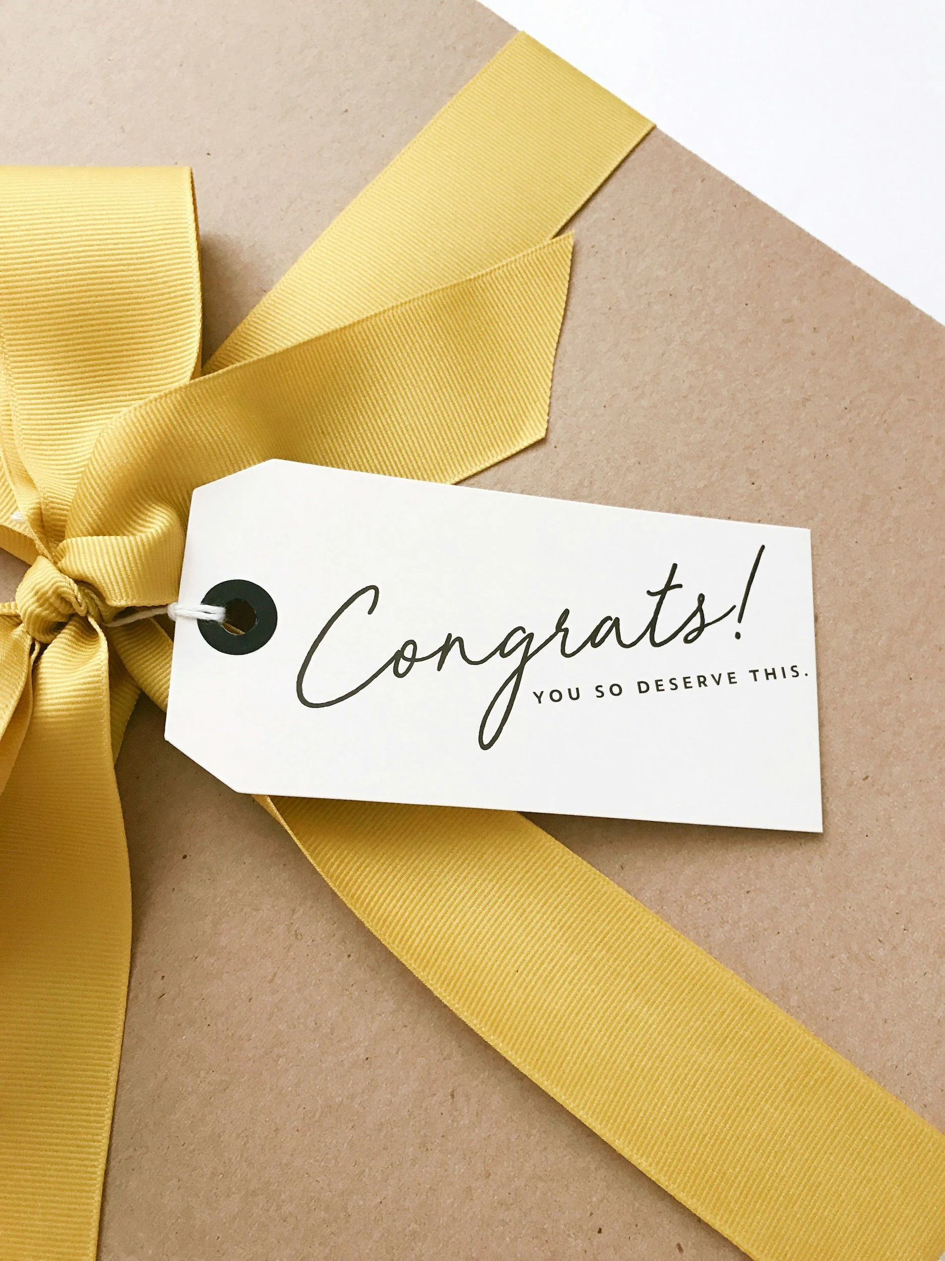 Gift box with yellow ribbon and congratulatory tag.