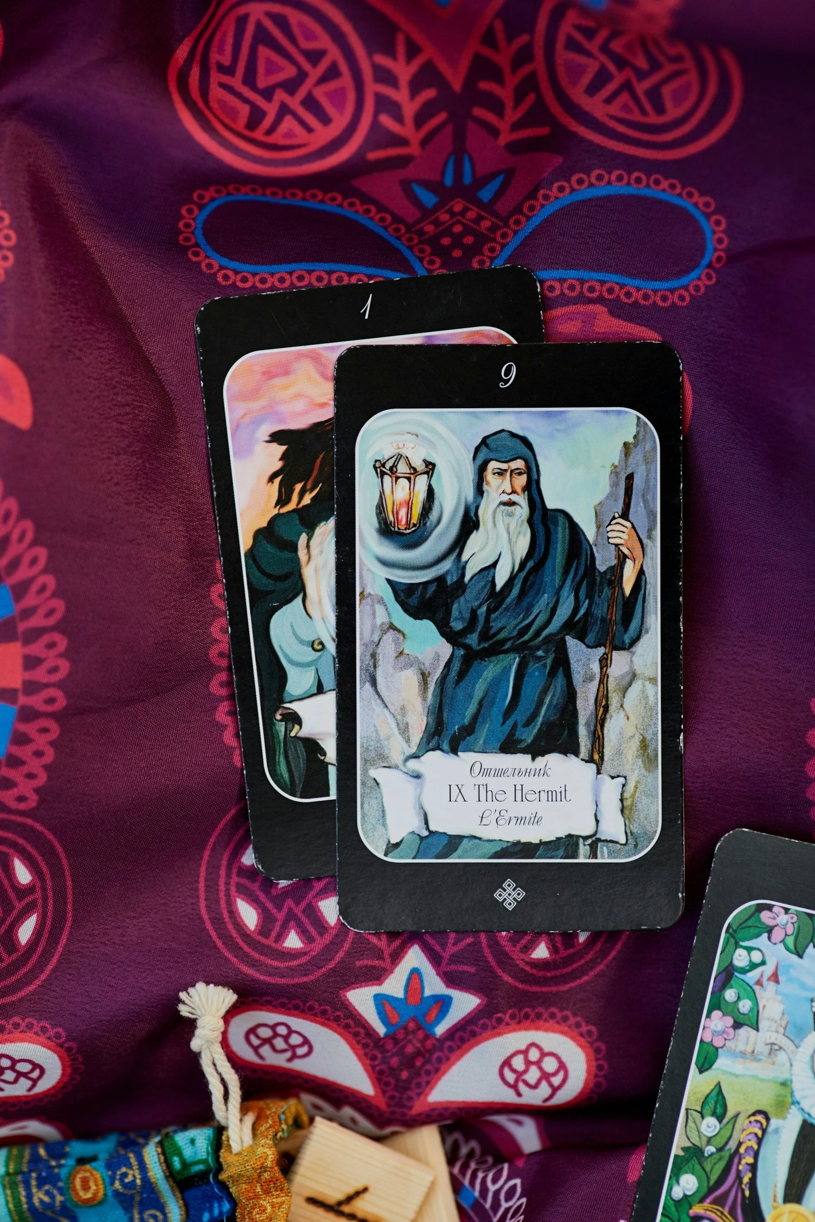 Person holding tarot cards over red fabric next to handwritten note on brown paper