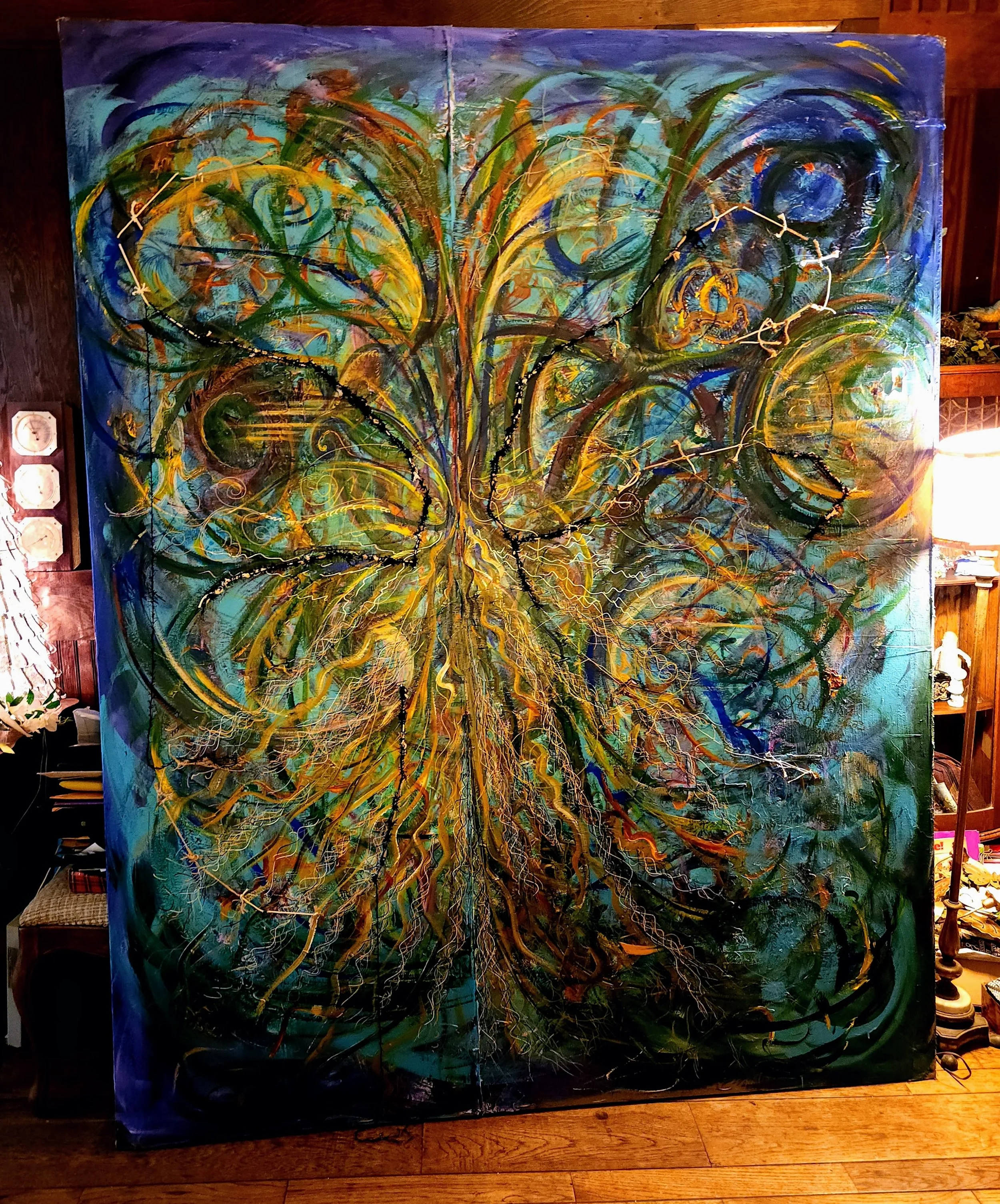 painting swirls of blue and yellow with brown threads woven onto the canvas