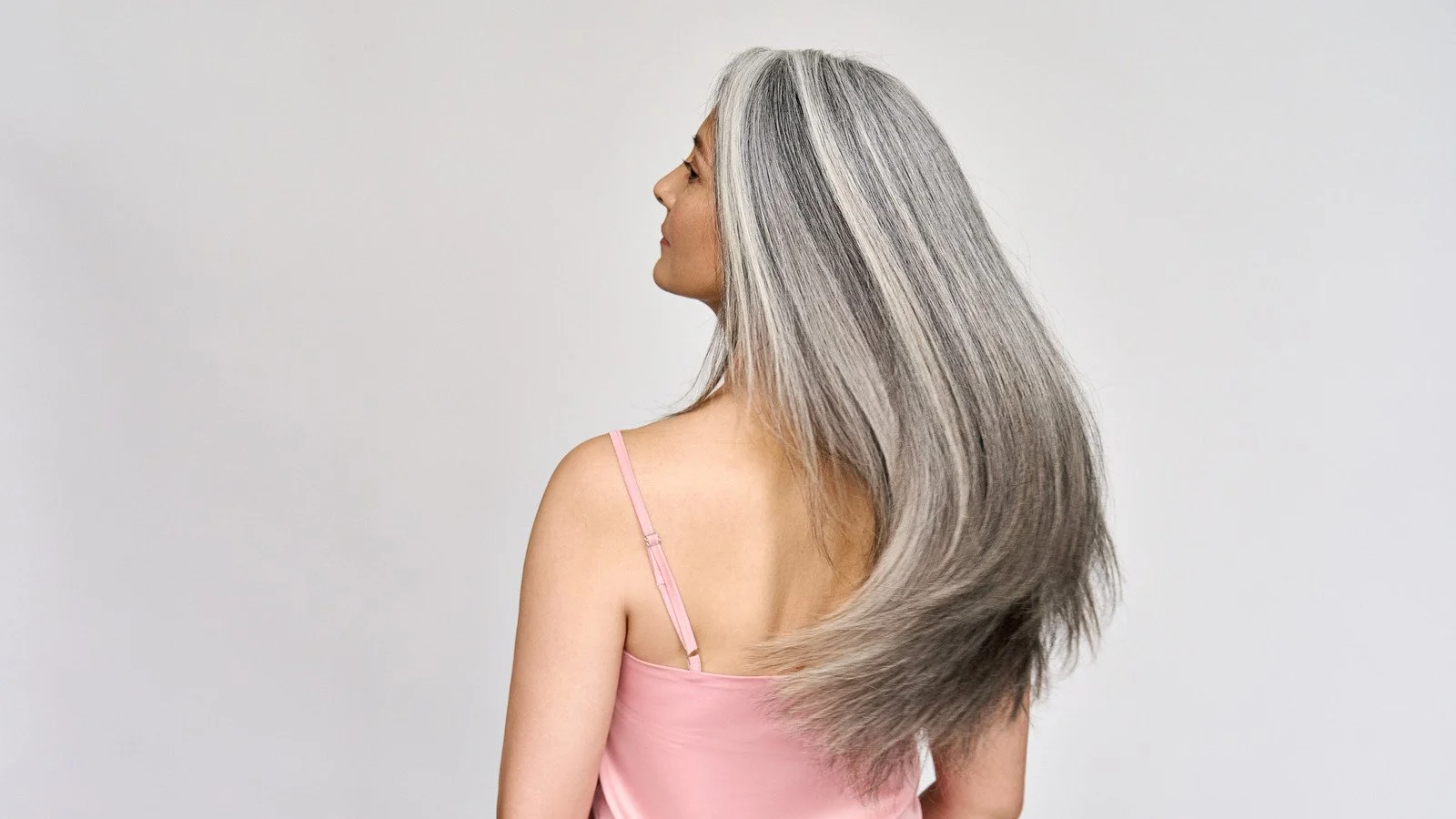Gray Blending growout can take up to six months or longer, but there are ways to make it less noticeable, Here a client has long gray hair and is about halfway grown out