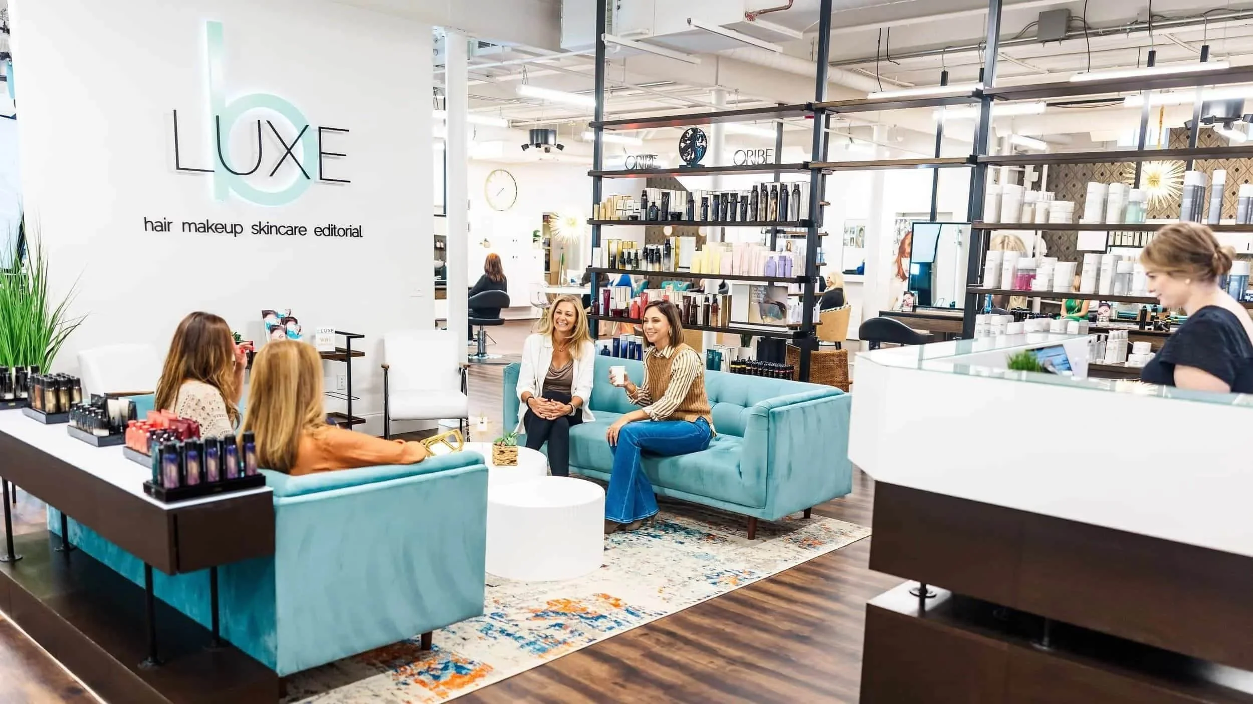 Here is an image of the bLUXE waiting area with its signature sign and teal couches. Guests are welcome to enjoy beverages and refreshments