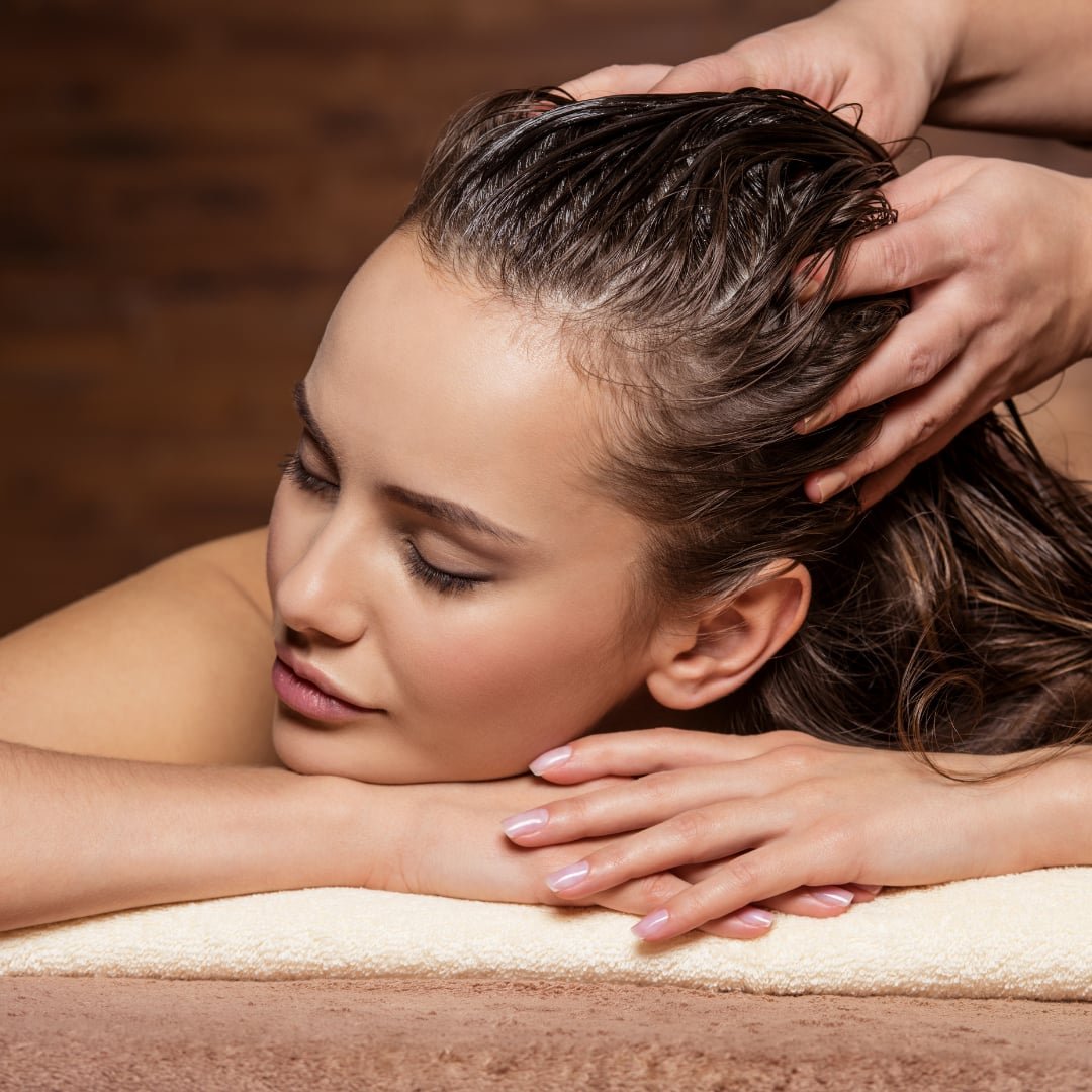 Here is an image of a client getting a scalp spa treatment. She is lying on the table and receives a scalp massage and scrub. She looks very relaxed