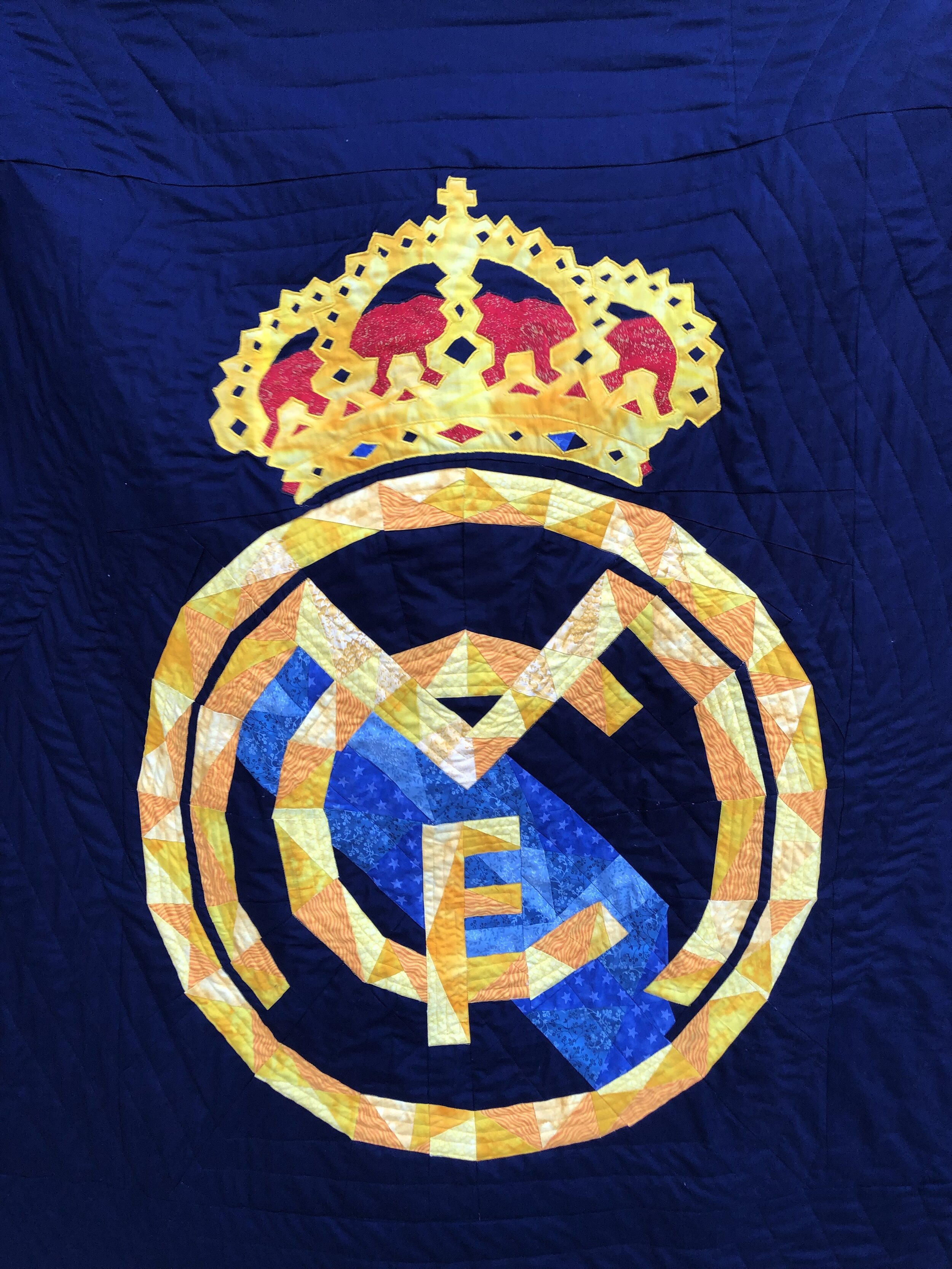 A quilt with the logo of FC Real Madrid intricately stitched into the fabric for a teen boy.