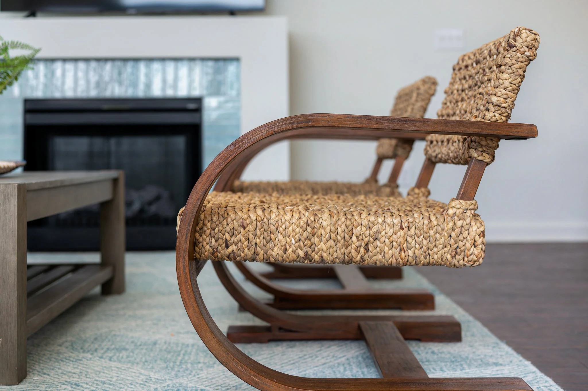 Close-up of a wooden rocking chair with a woven rattan seat and backrest in a modern living room.