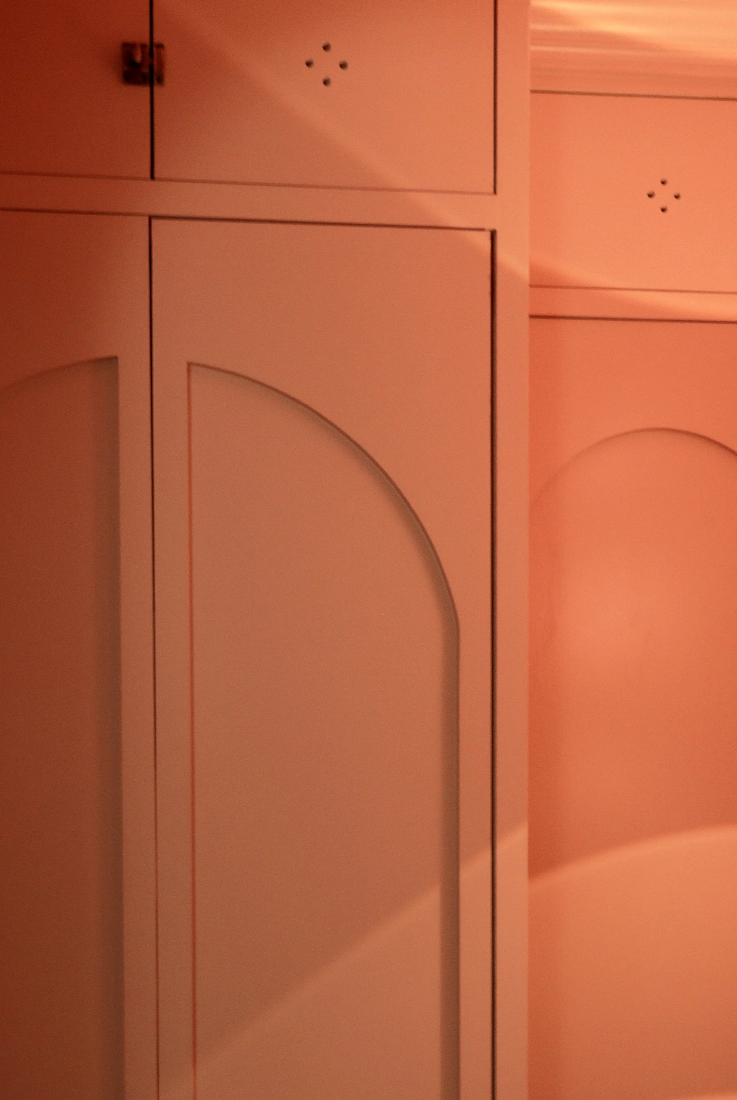 Close-up of a terracotta limewash painted cabinet with black dots and a curved design on the door.