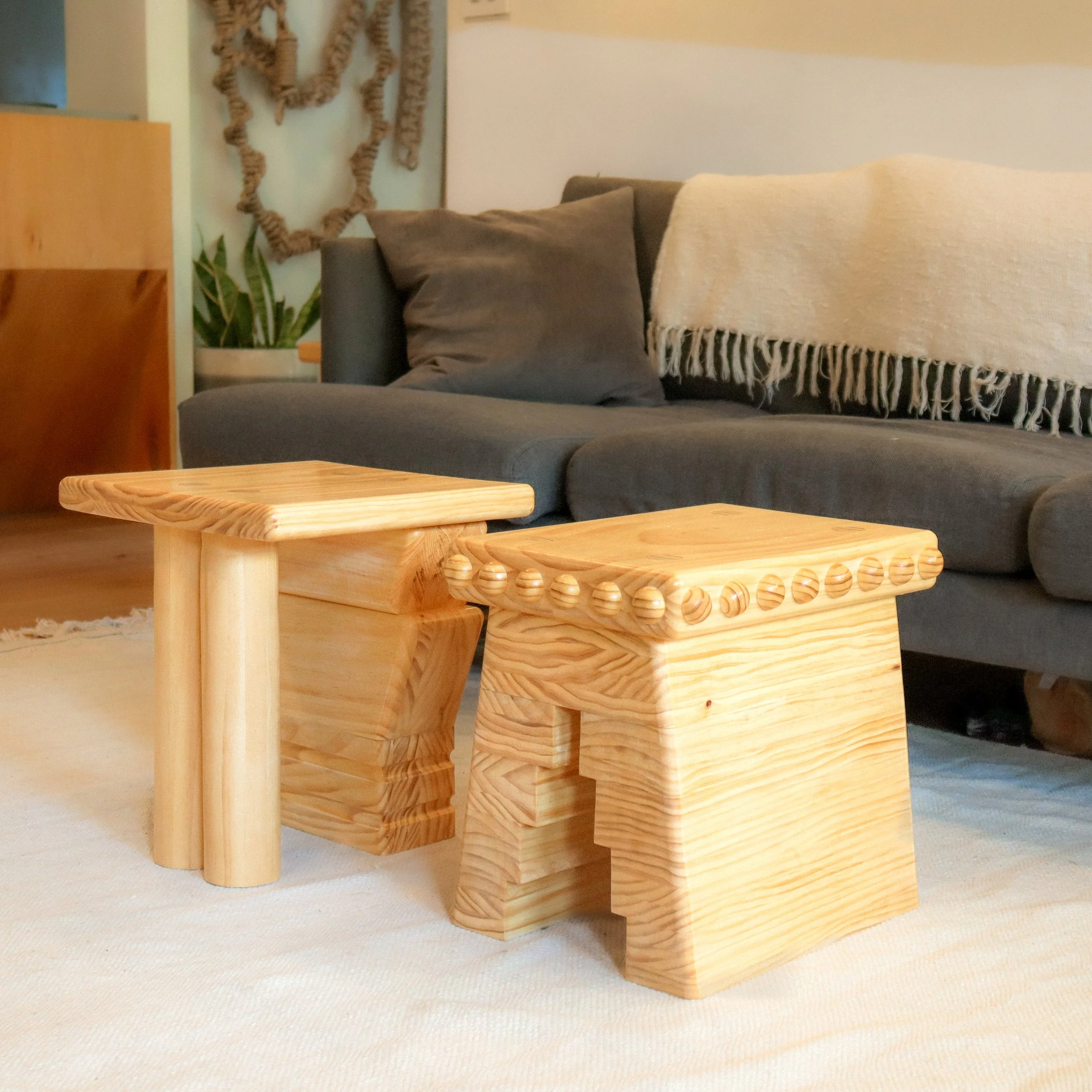 A close-up view of a wooden furniture piece with rounded edges and a circular pattern of holes, situated on a beige carpeted floor.