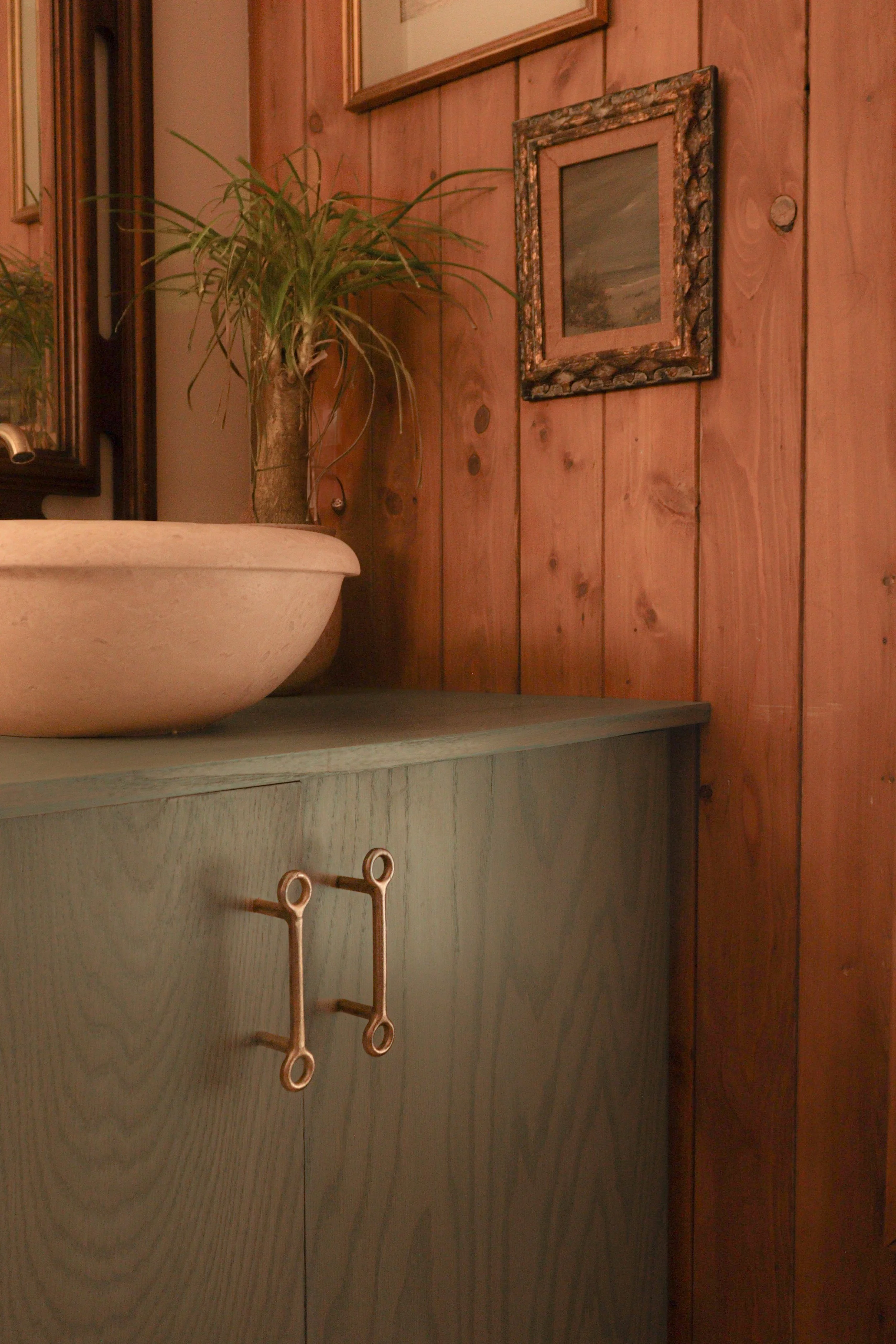 Cottage style bathroom renovation in Kitty Hawk with custom blue stained vanity , travertine sink and original wood panel wall