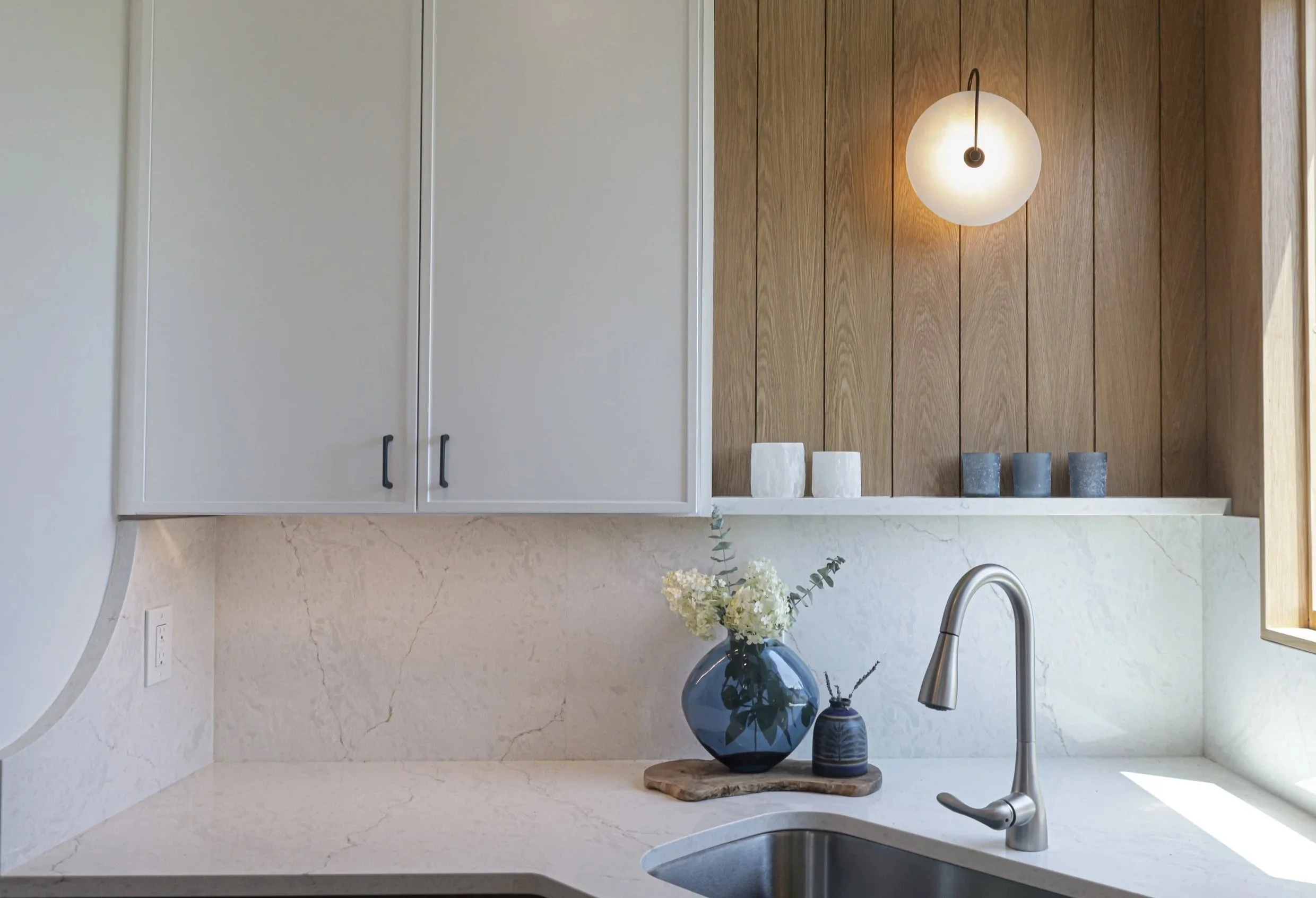 Kitchen remodel in Manteo with white slim shaker cabinets, white oak shiplap, modern sconce light and white Cristallo quartz countertop and backsplash 