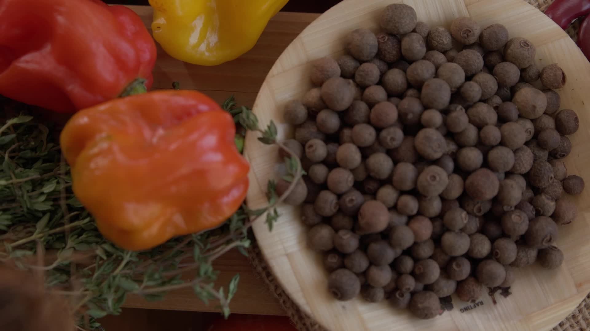 Mixed peppers with allspice berries on wooden surface