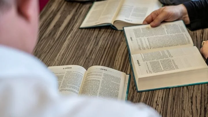 group of men gathered around Bibles open on a table
