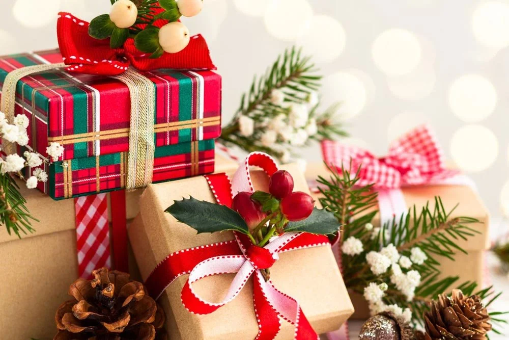 stack of wrapped Christmas gifts and greenery