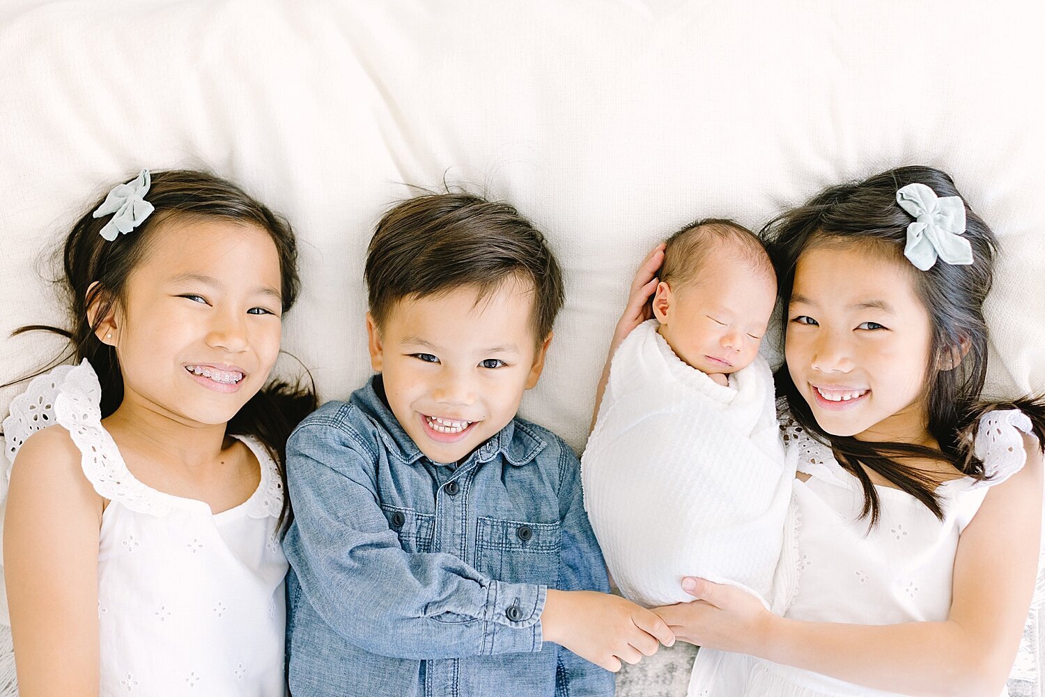 Four siblings laying together for baby brothers newborn photos with Ambre Williams in Newport Beach, CA.