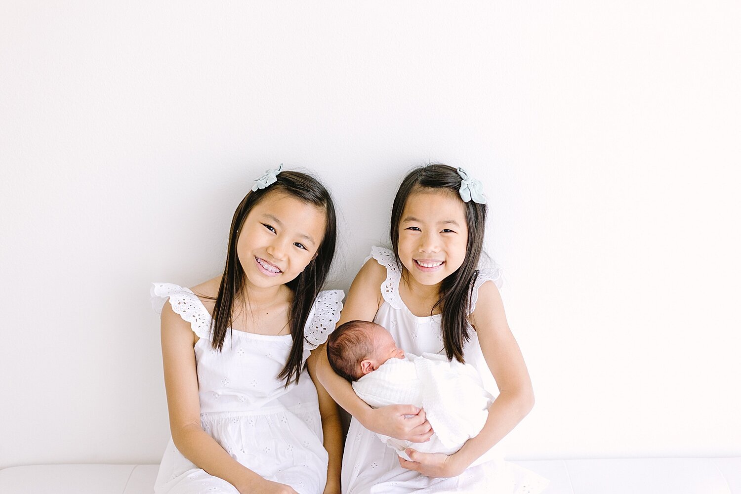 Two proud big sisters holding their baby brother | Ambre Williams Photography