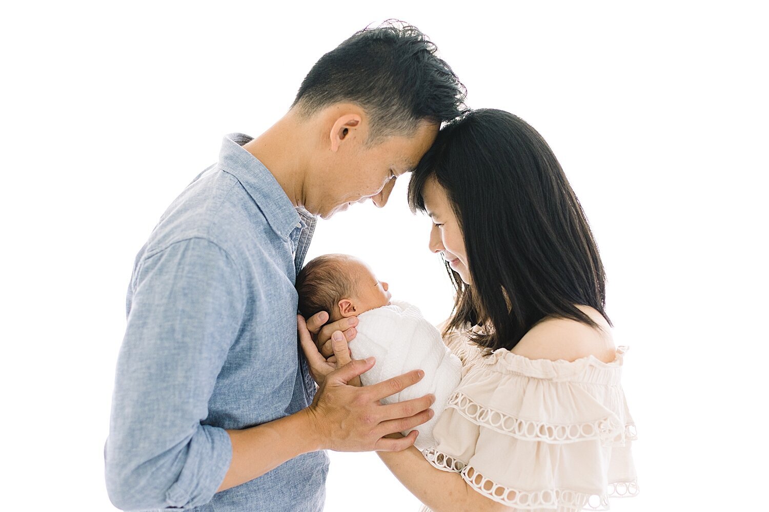 Mom and Dad with their newborn son in Newport Beach photography studio. Photo by Ambre Williams Photography.