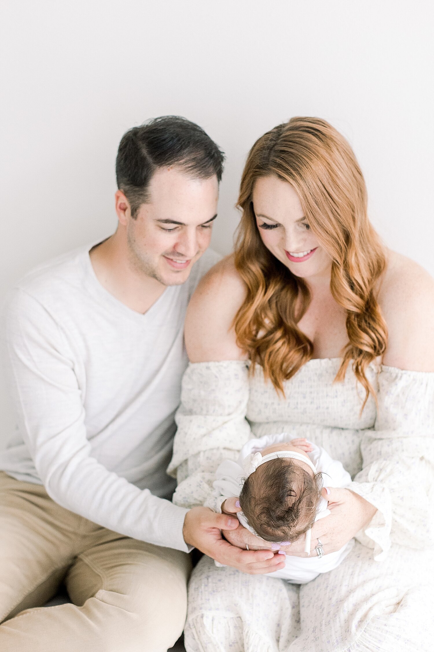 Parents adoring their newborn baby girl in photography studio in Newport Beach. Photo by Ambre Williams Photography.