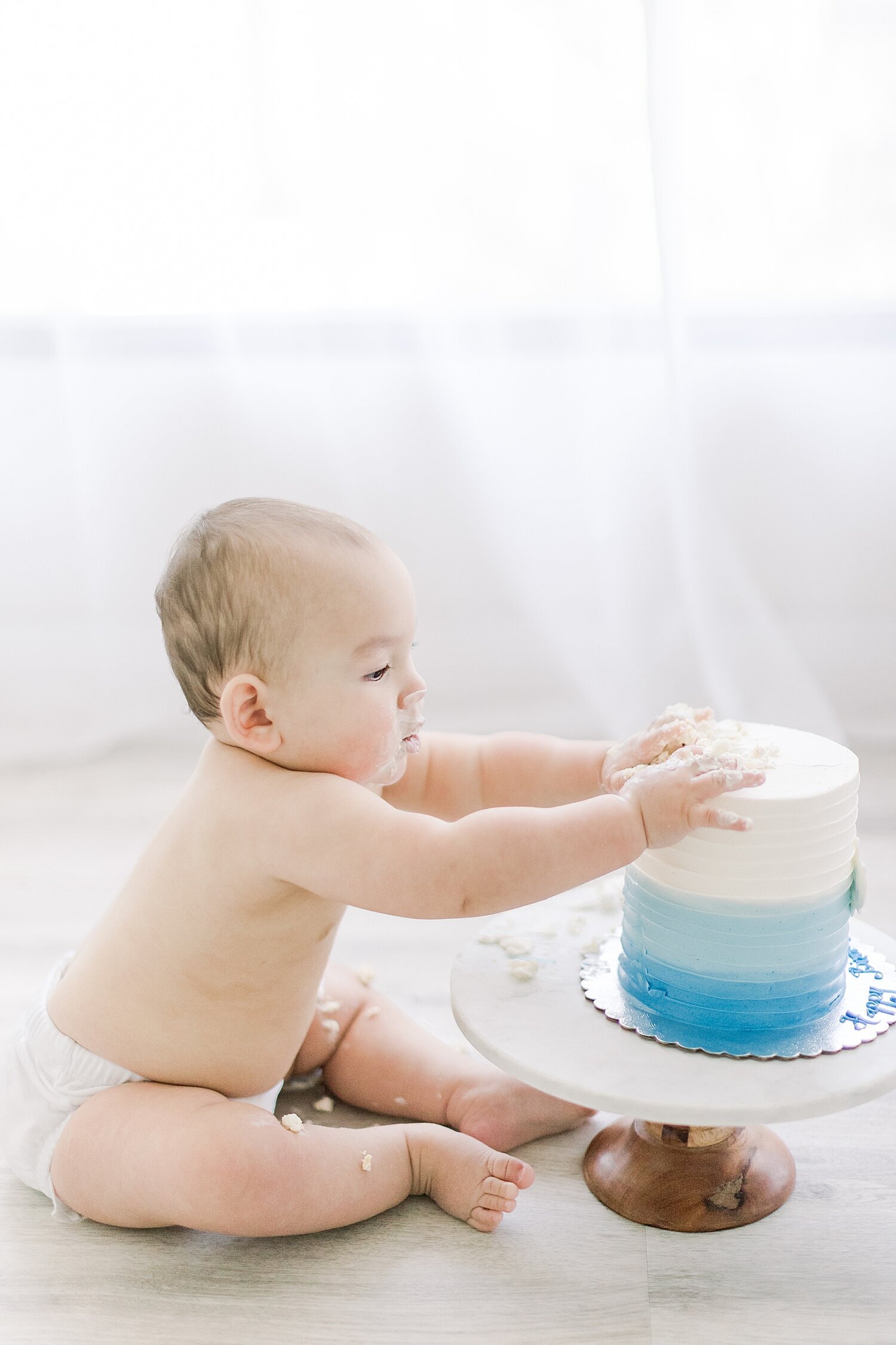 One year old playing in cake first cake smash session. Photo by Ambre Williams Photography.
