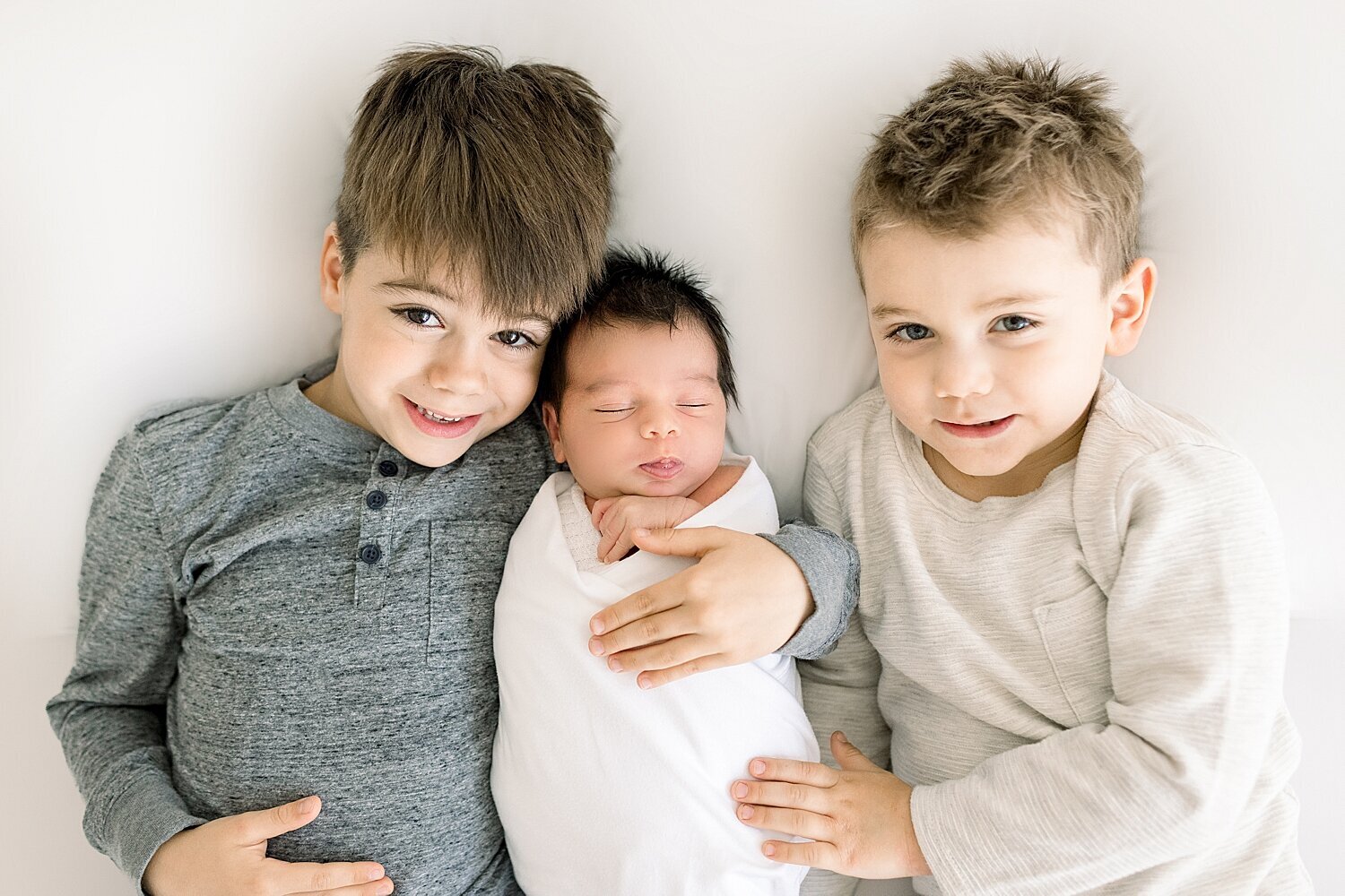 Three brothers laying together during newborn session for youngest brother. Photo by Ambre Williams Photography.