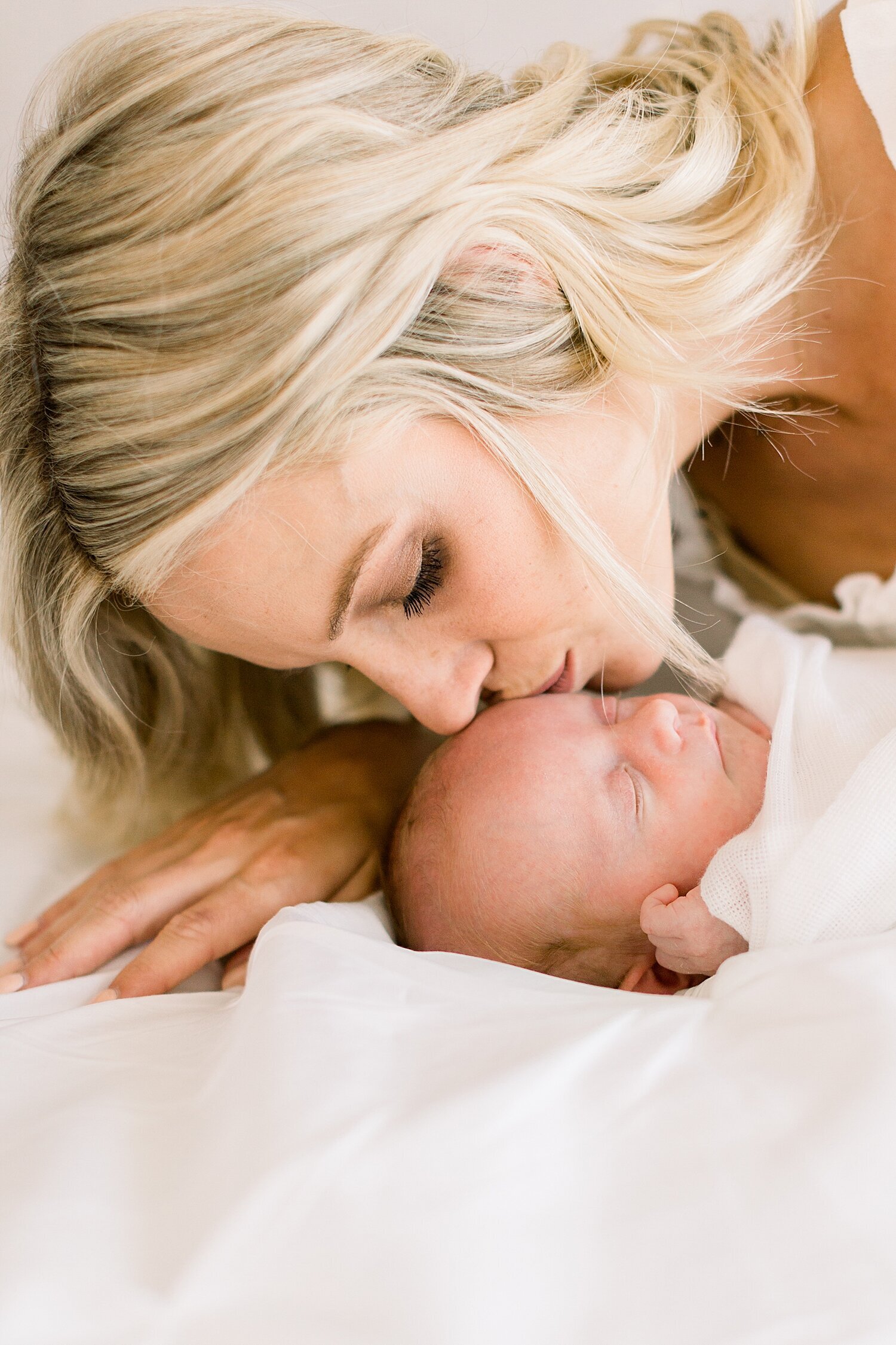 Mom kissing baby boy during his newborn session with Ambre Williams Photography.
