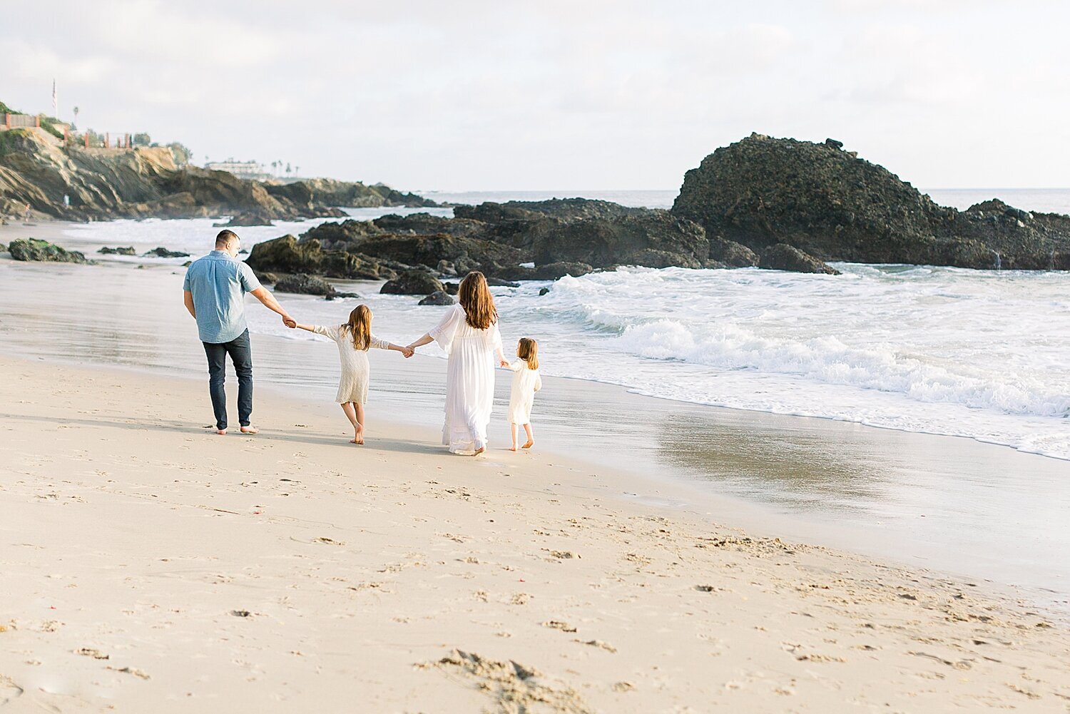 Family walking along the surf at Corona del Mar during a maternity photoshoot with Ambre Williams Photography.