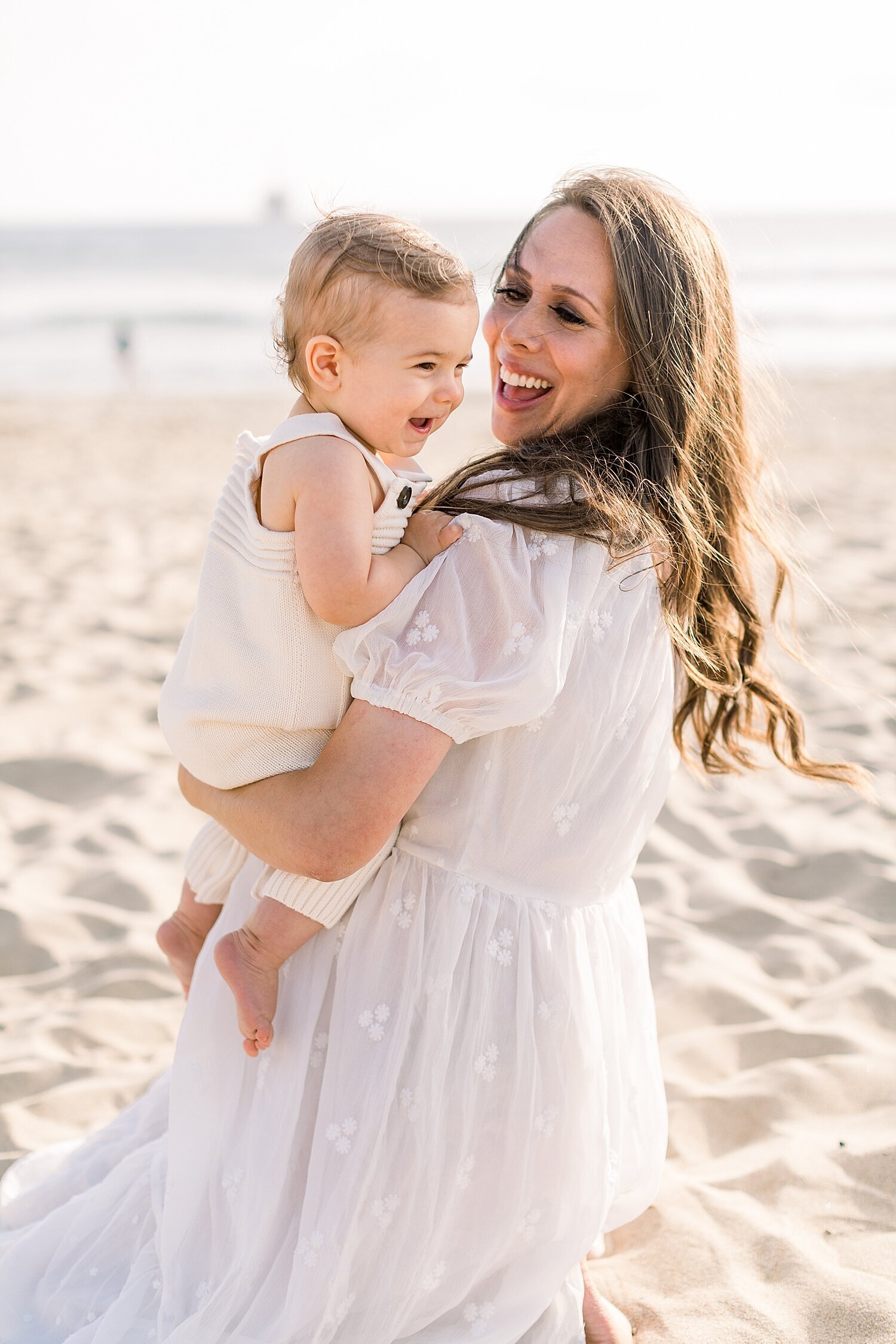 Mama and baby boy laughing on the beach during maternity session. Photos by Ambre Williams Photography. 