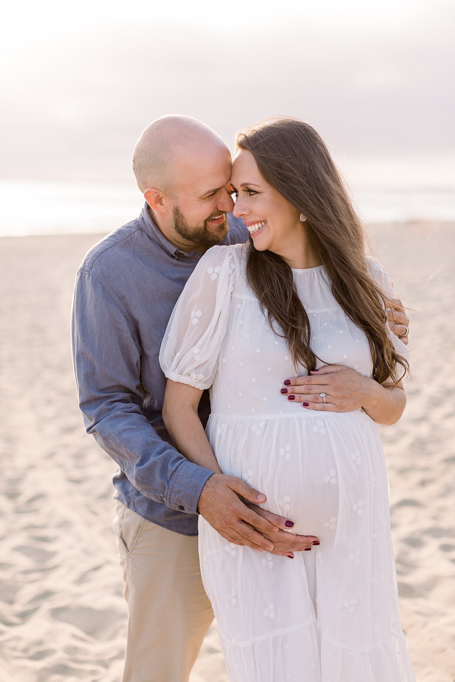 Photo of Mom and Dad during sunset maternity session at Huntington Beach. Photos by Ambre Williams Photography.