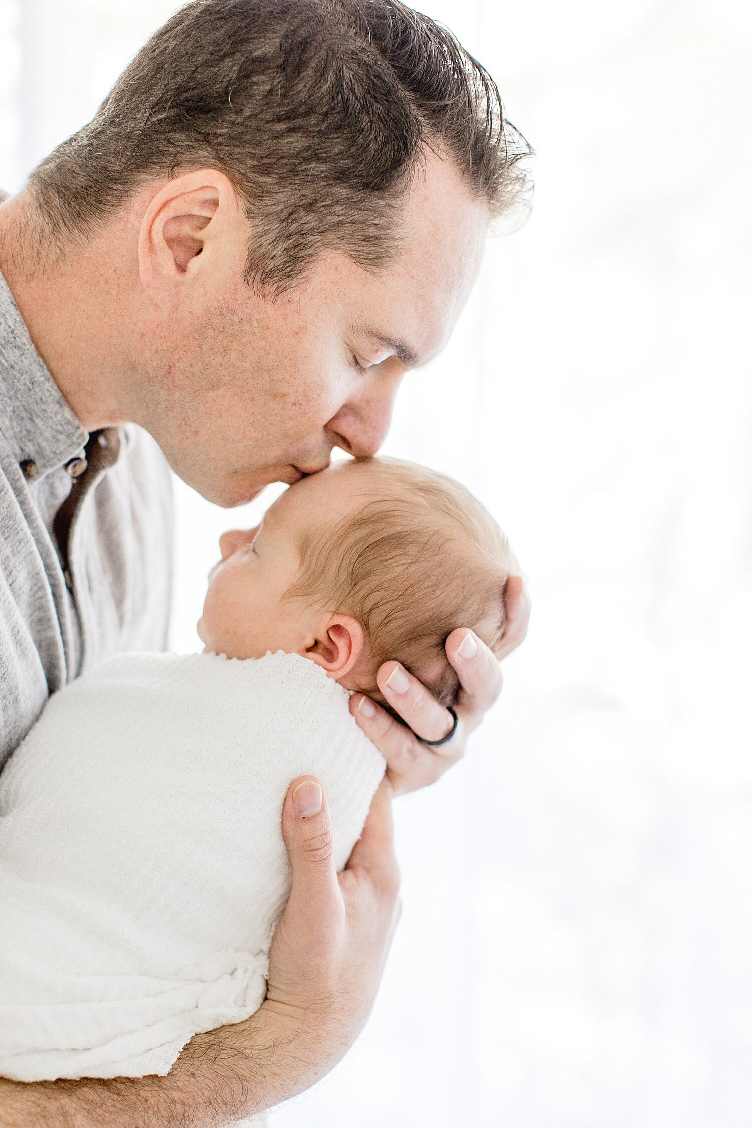 Dad kissing son during newborn session. Photo by Ambre Williams Photography.
