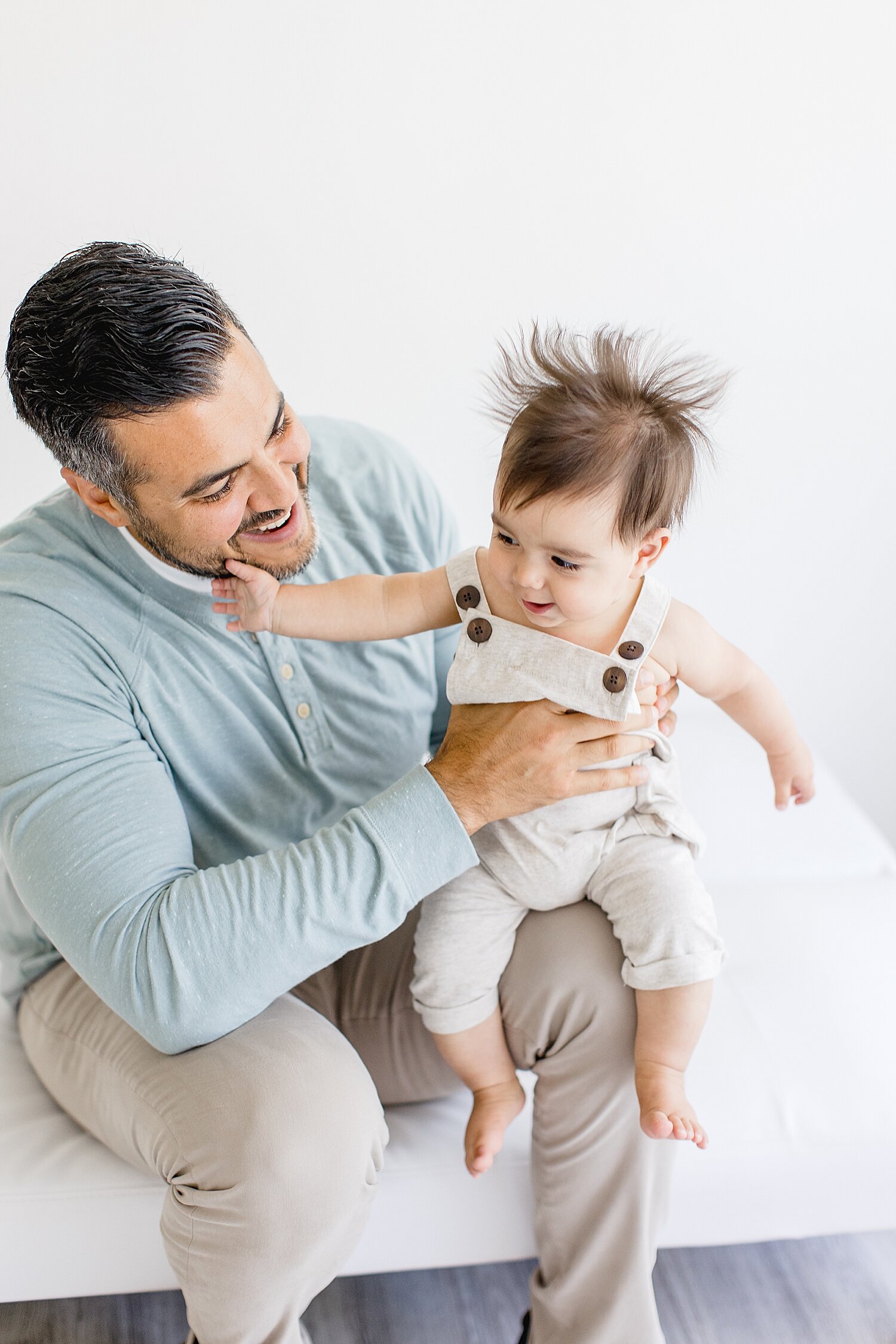 Dad holding son with wild hair during six month session with Ambre Williams Photography.