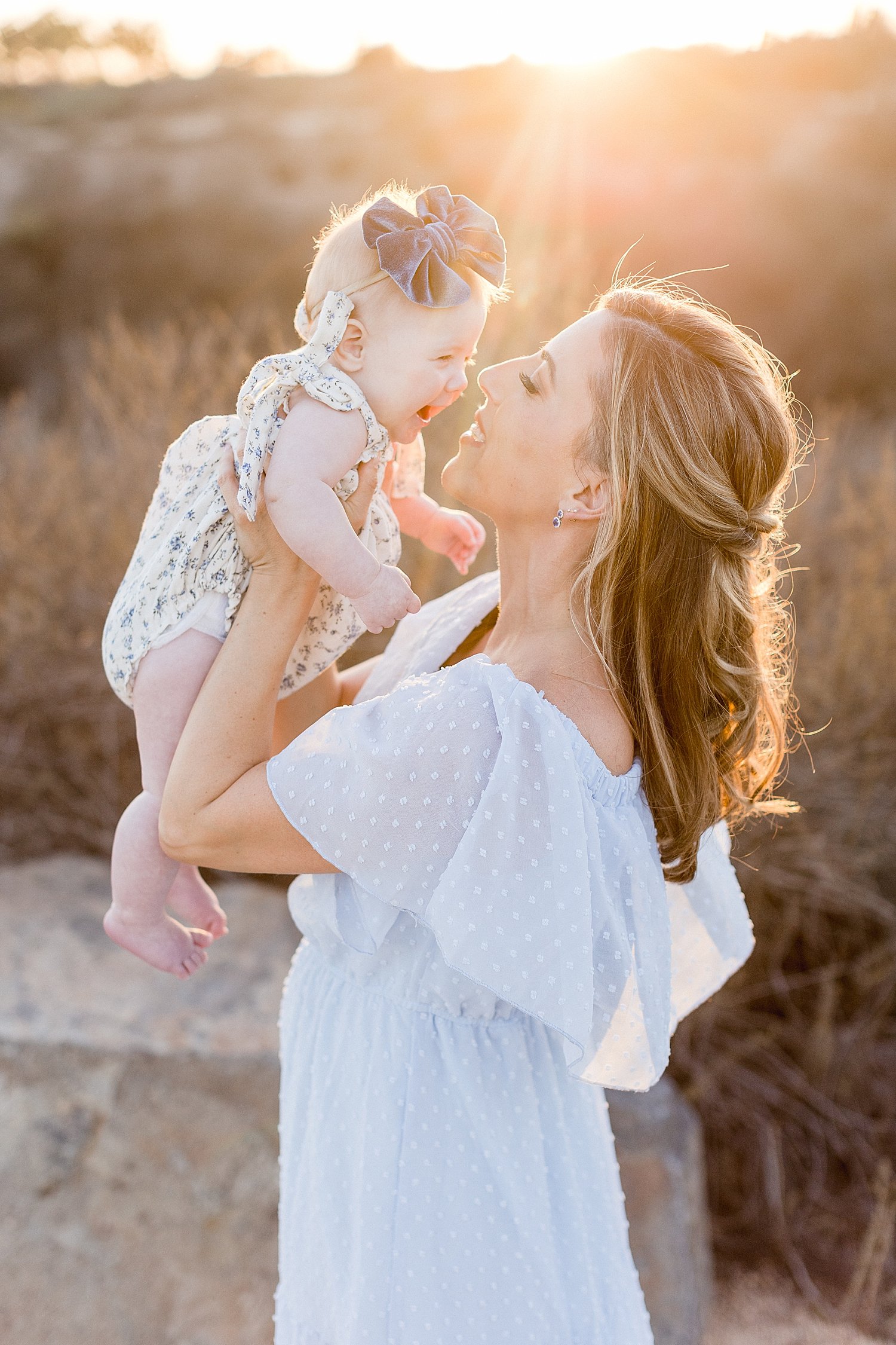 Mom holding her baby girl up and kissing her | Photo by Ambre Williams Photography
