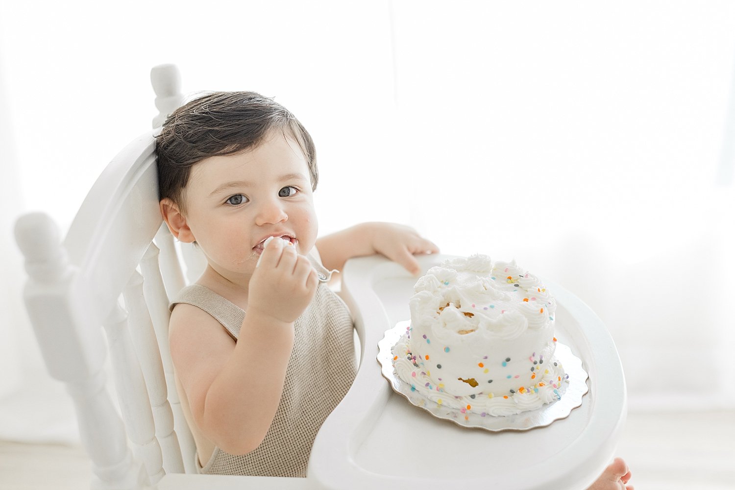 One year old sitting in high chair for cake smash session. Photo by Ambre Williams Photography.