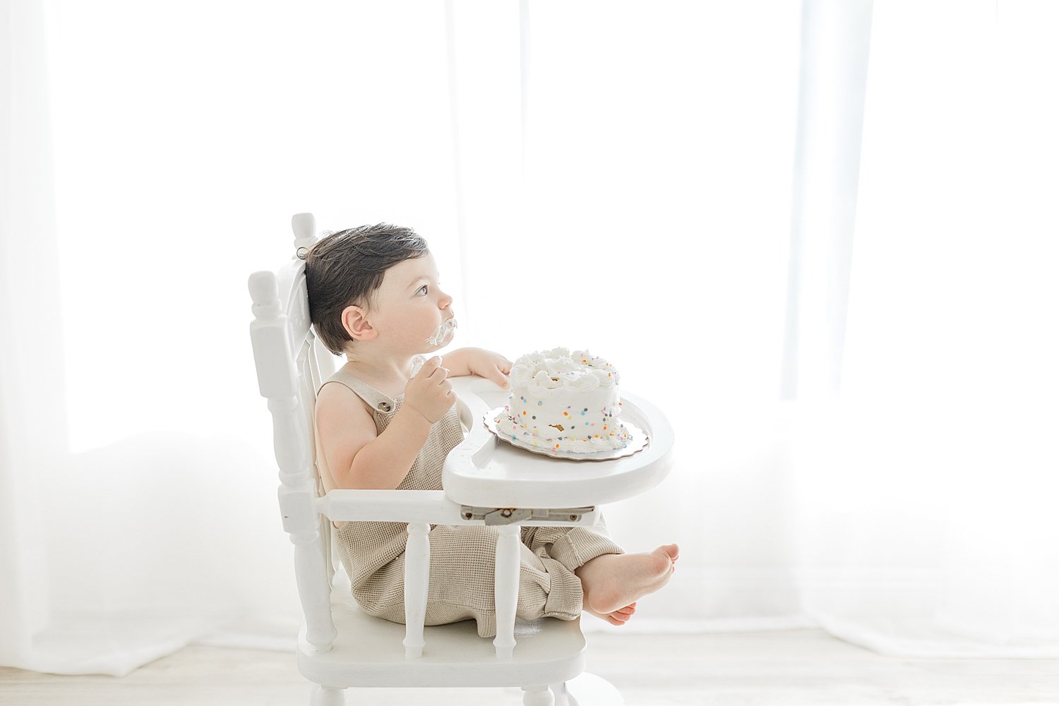 One year old sitting in high chair for cake smash session. Photo by Ambre Williams Photography.