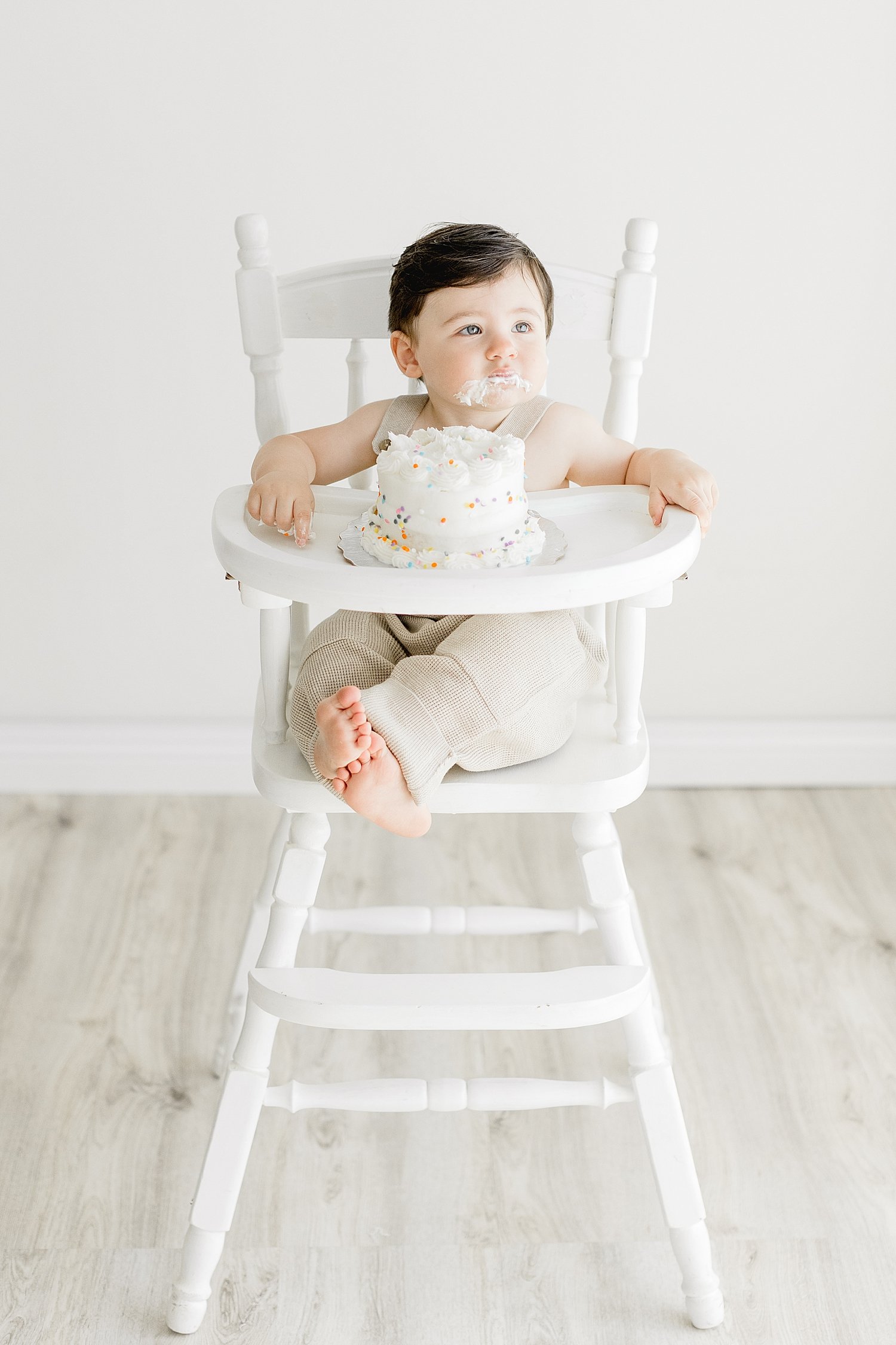 One year old sitting in high chair for cake smash session. Photo by Ambre Williams Photography.