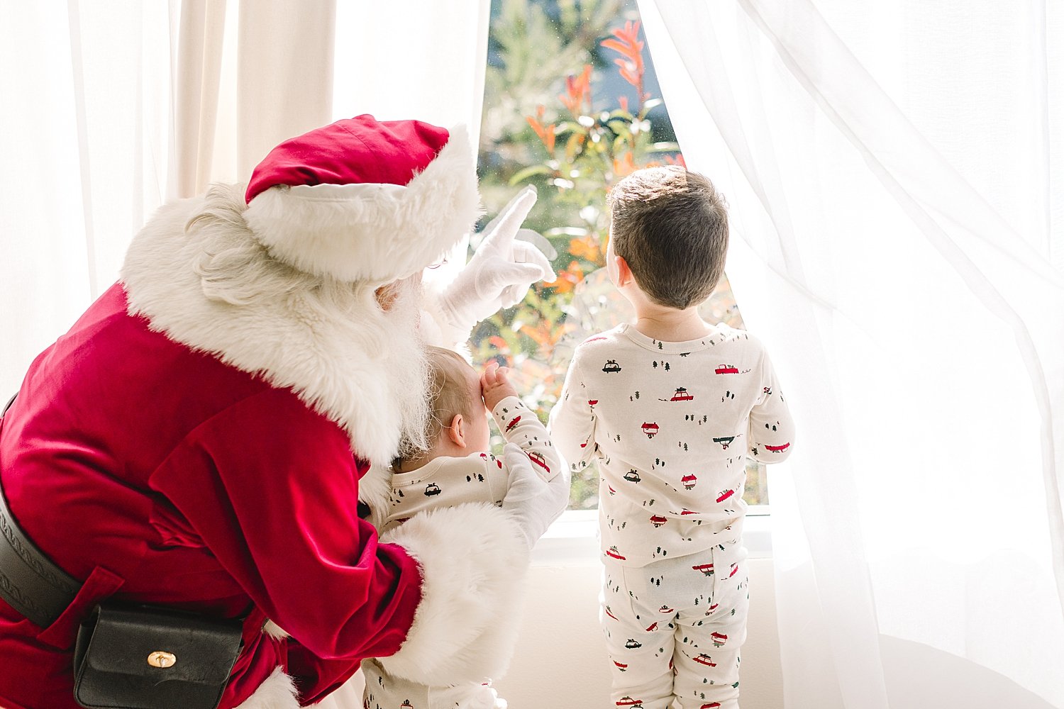 Santa looking outside window with young children | Ambre Williams Photography.