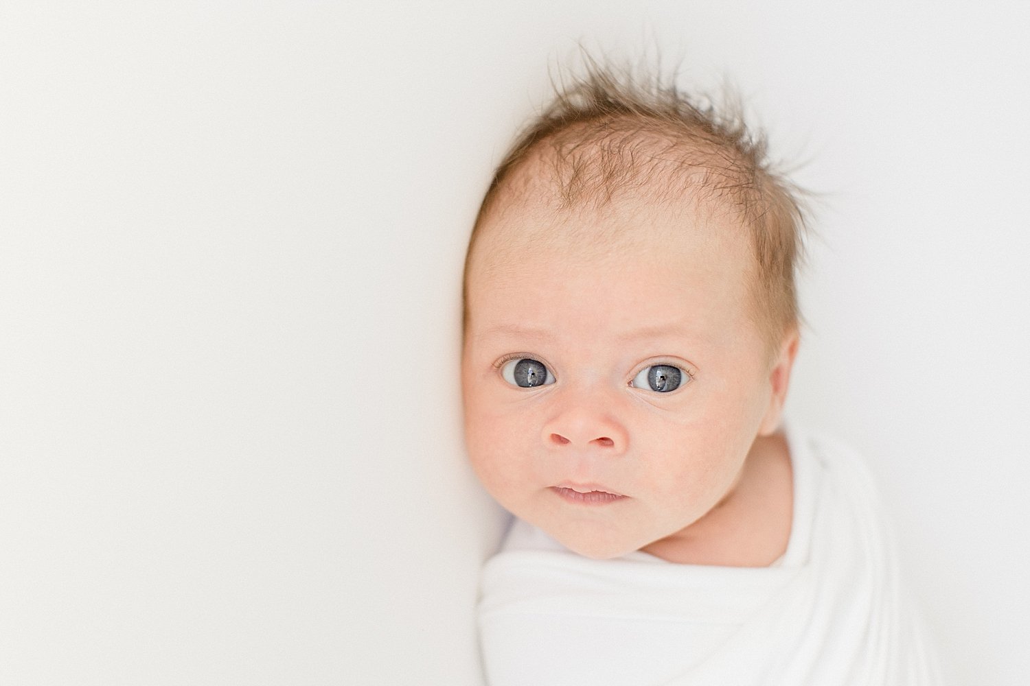 Baby boy with eyes wide open for newborn session with Ambre Williams Photography.