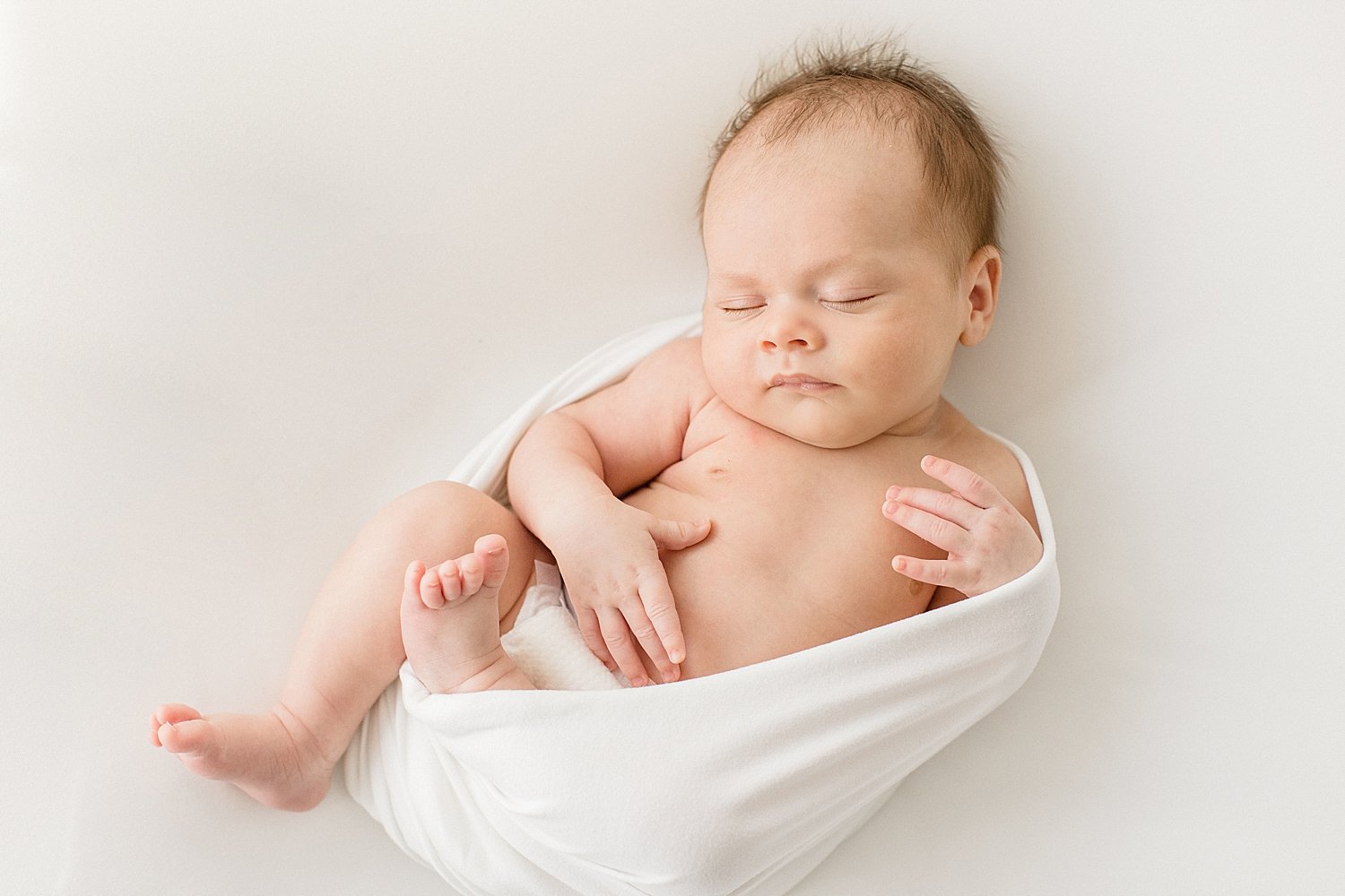 Baby boy swaddled in white for newborn session with Ambre Williams Photography.