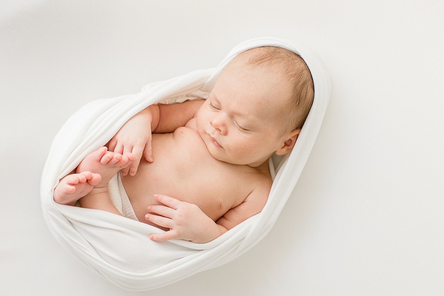 Baby boy swaddled in white for newborn session with Ambre Williams Photography.
