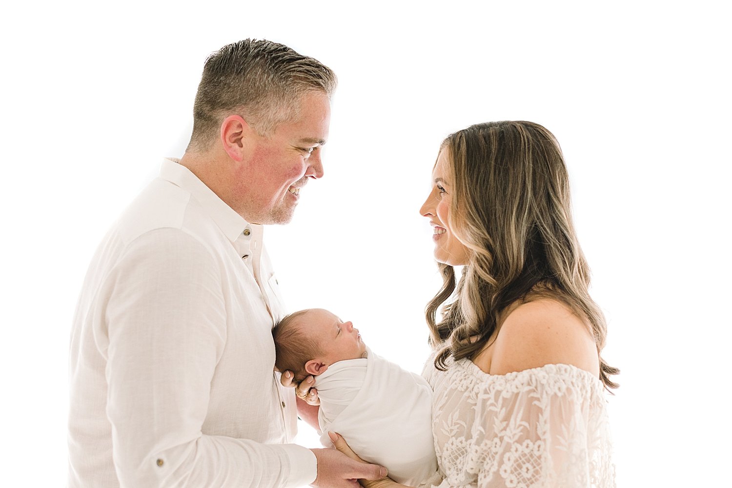 Mom and Dad looking at each other while holding their baby boy for his newborn photos with Ambre Williams Photography.