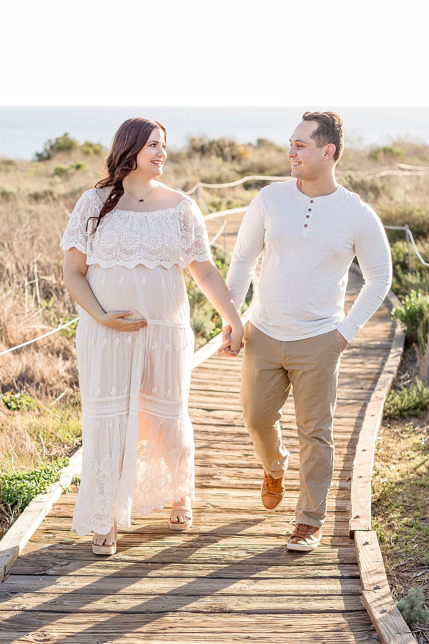 Couple walking along path to Crystal Cove beach during maternity session | Ambre Williams Photography