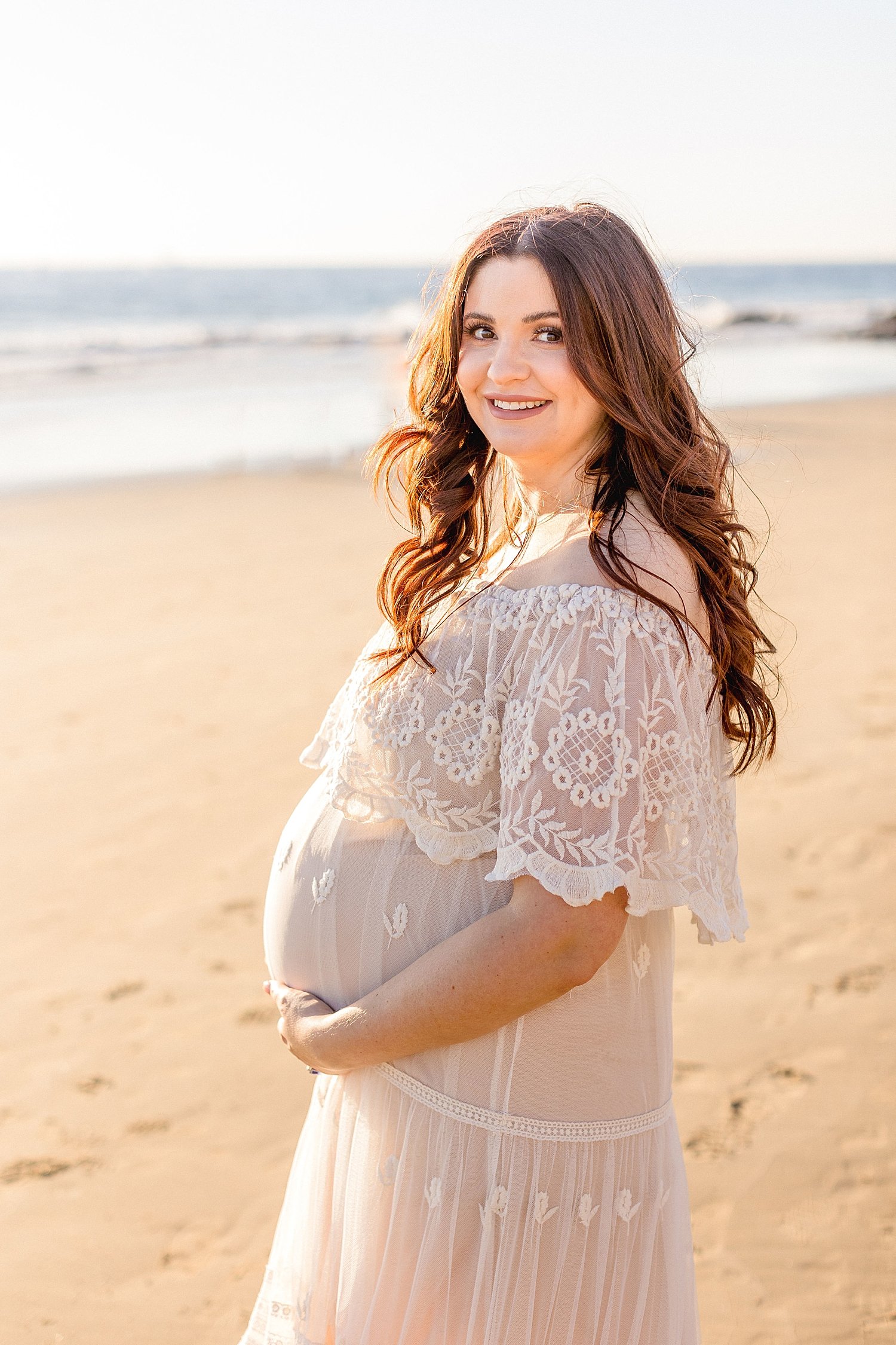 Pregnant Mom on the beach in lace dress for maternity portraits with Ambre Williams Photography.