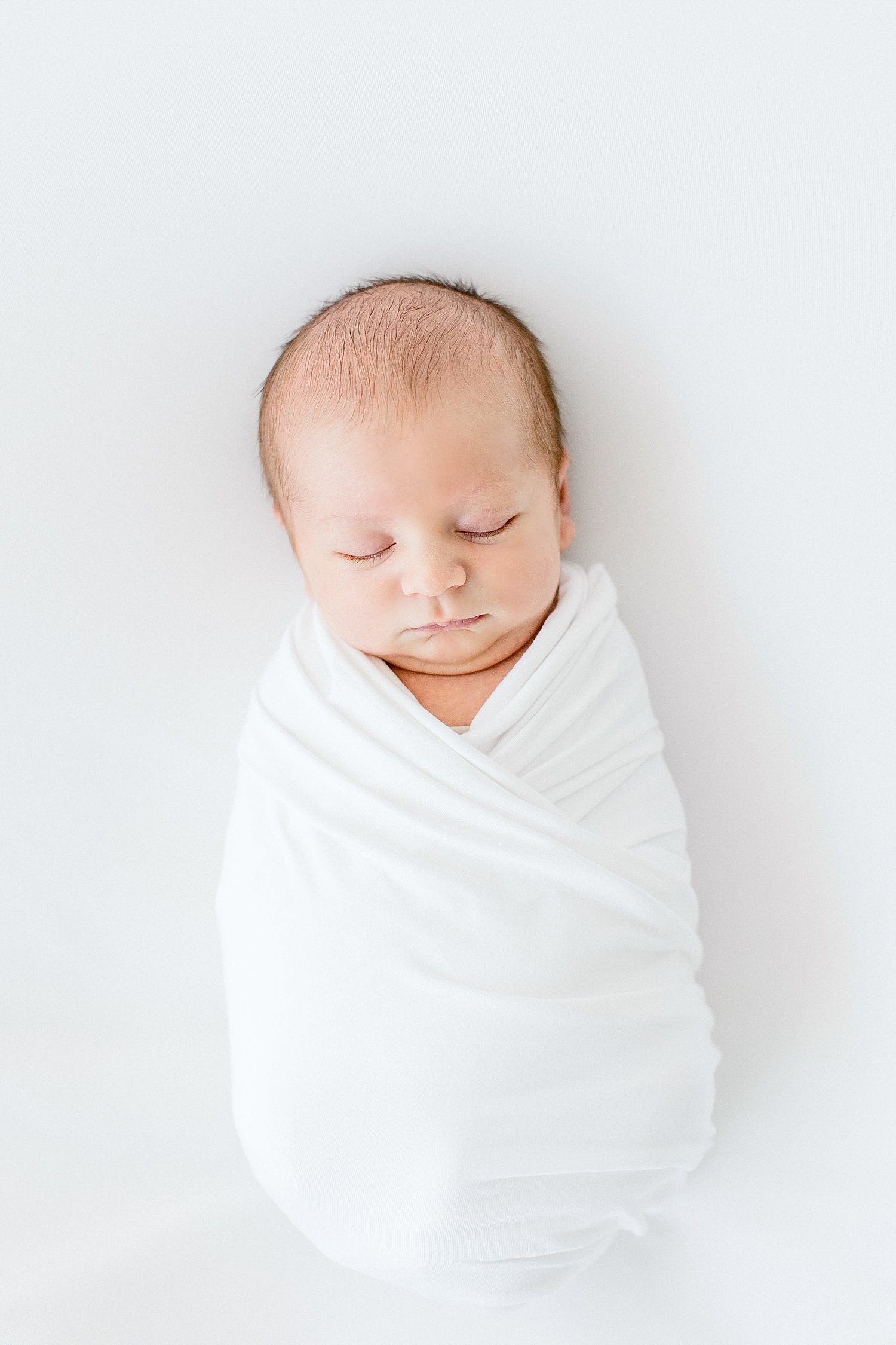 Newborn baby boy swaddled in white | Ambre Williams Photography