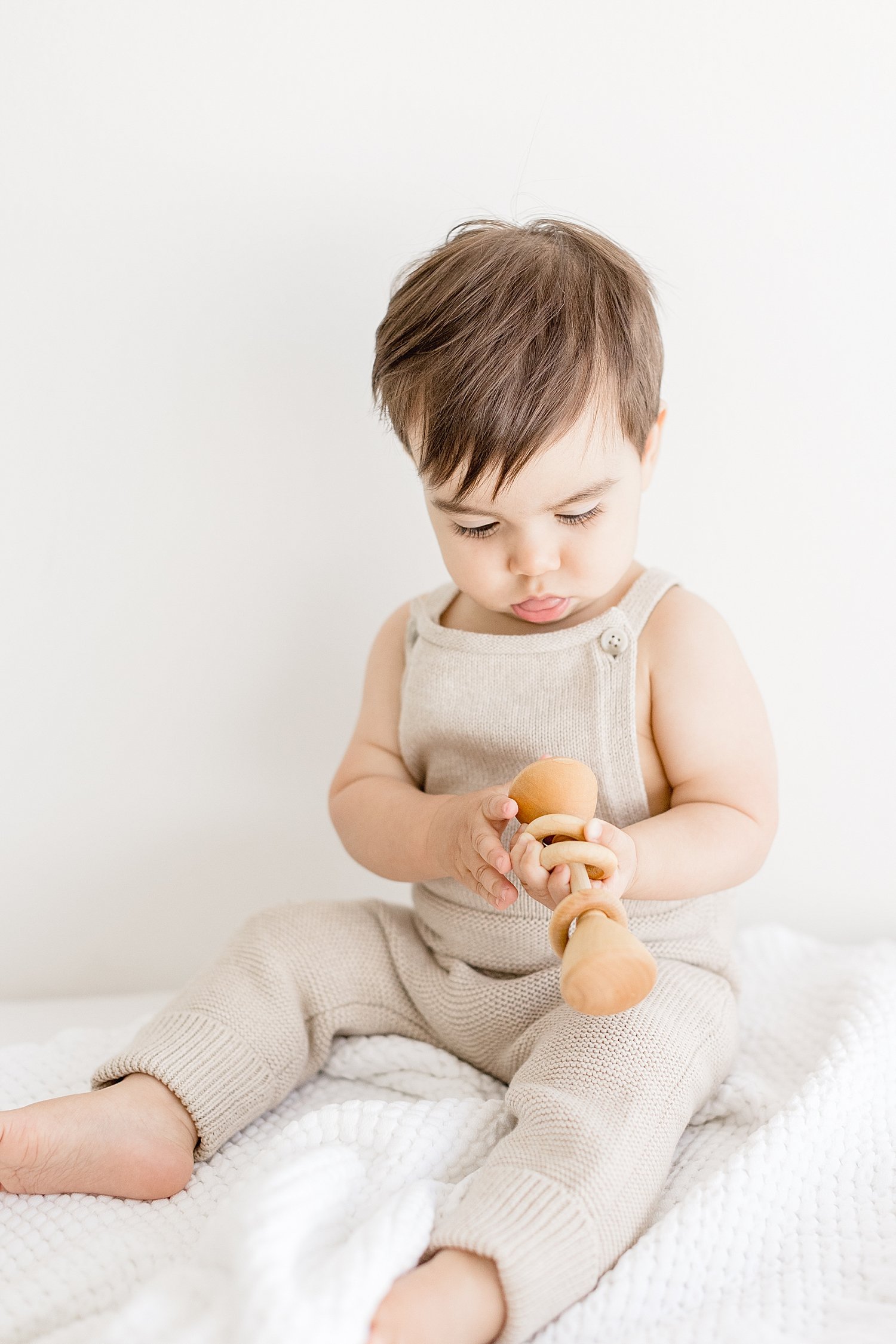 One year old boy playing with wood rattle | Ambre Williams Photography