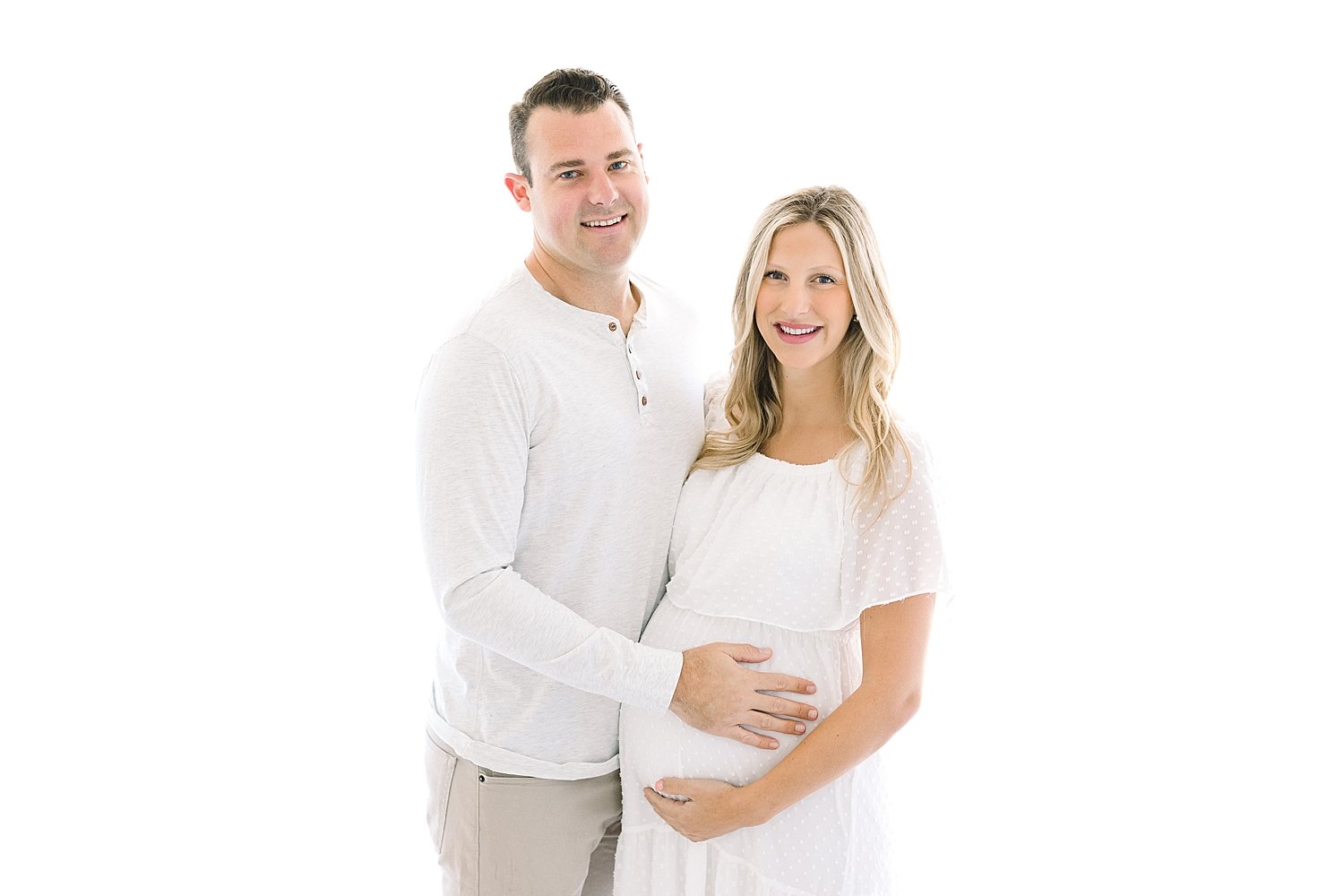 First-time expecting parents wearing all white for studio maternity session with Ambre Williams Photography.