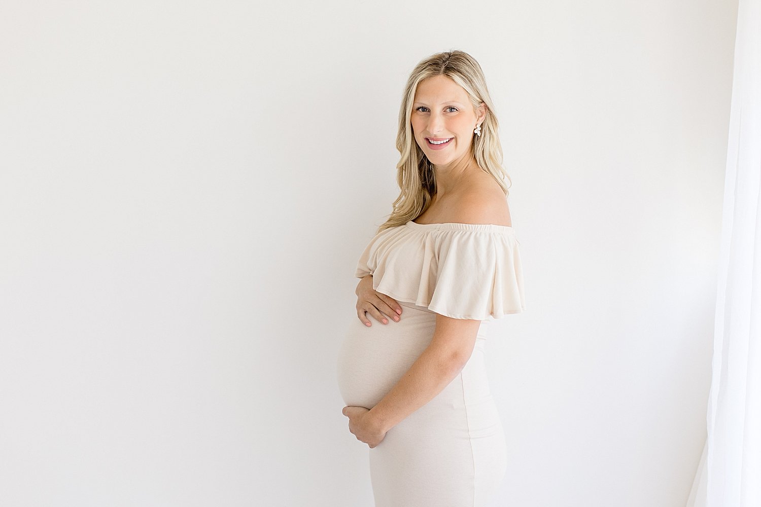 Mom holding pregnant belly for maternity photos in studio in Newport Beach | Ambre Williams Photography
