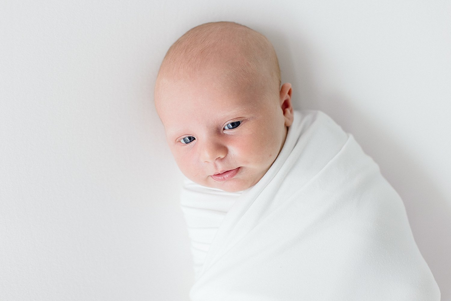 Baby boy with eyes open during newborn session with Ambre Williams Photography. 